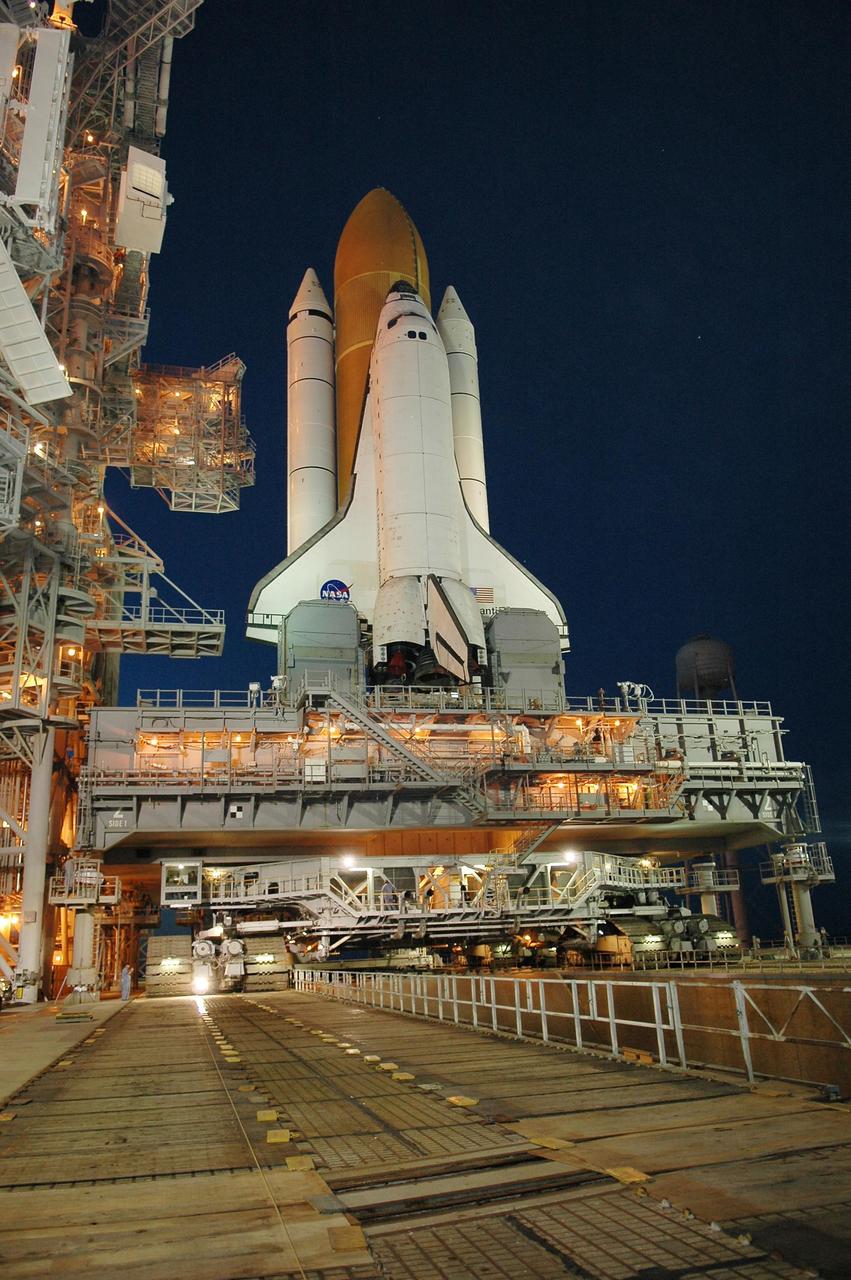 KENNEDY SPACE CENTER, FLA. - After sunset, Space Shuttle Atlantis is bathed in light from the fixed service structure on Launch Pad 39B. Seen on either side of Atlantis' engine nozzles are the tail masts, which provide several umbilical connections to the orbiter, including a liquid-oxygen line through one and a liquid-hydrogen line through another.  The shuttle had been moved off the launch pad due to concerns about the impact of Tropical Storm Ernesto, expected within 24 hours.  The forecast of lesser winds expected from Ernesto and its projected direction convinced Launch Integration Manager LeRoy Cain and Shuttle Launch Director Mike Leinbach to return the shuttle to the launch pad.   Photo credit: NASA/Kim Shiflett