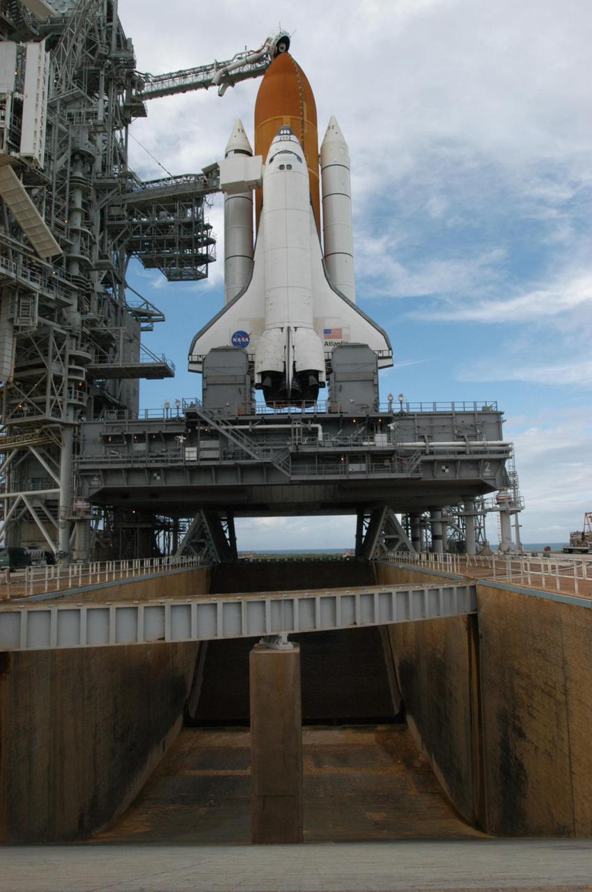 KENNEDY SPACE CENTER, FLA. - After rollback of the rotating service structure on Launch Pad 39B, Space Shuttle Atlantis is revealed. The RSS provides protected access to the orbiter for changeout and servicing of payloads at the pad and then is rolled away before liftoff. Seen above the golden external tank is the vent hood (known as the "beanie cap") at the end of the gaseous oxygen vent arm. Vapors are created as the liquid oxygen in the external tank boil off. The hood vents the gaseous oxygen vapors away from the space shuttle vehicle. Below it, extending from the fixed service structure, is the orbiter access arm with the White Room at the end. The White Room provides entry into the orbiter. Atlantis is scheduled to launch Sept. 6 at 12:29 p.m. EDT on mission STS-115. During the mission, Atlantis' astronauts will deliver and install the 17.5-ton, bus-sized P3/P4 integrated truss segment on the station. The girder-like truss includes a set of giant solar arrays, batteries and associated electronics and will provide one-fourth of the total power-generation capability for the completed station. This mission is the 116th space shuttle flight, the 27th flight for orbiter Atlantis, and the 19th U.S. flight to the International Space Station. STS-115 is scheduled to last 11 days with a planned KSC landing at about 8:03 a.m. EDT on Sept. 17. Photo credit: NASA/George Shelton