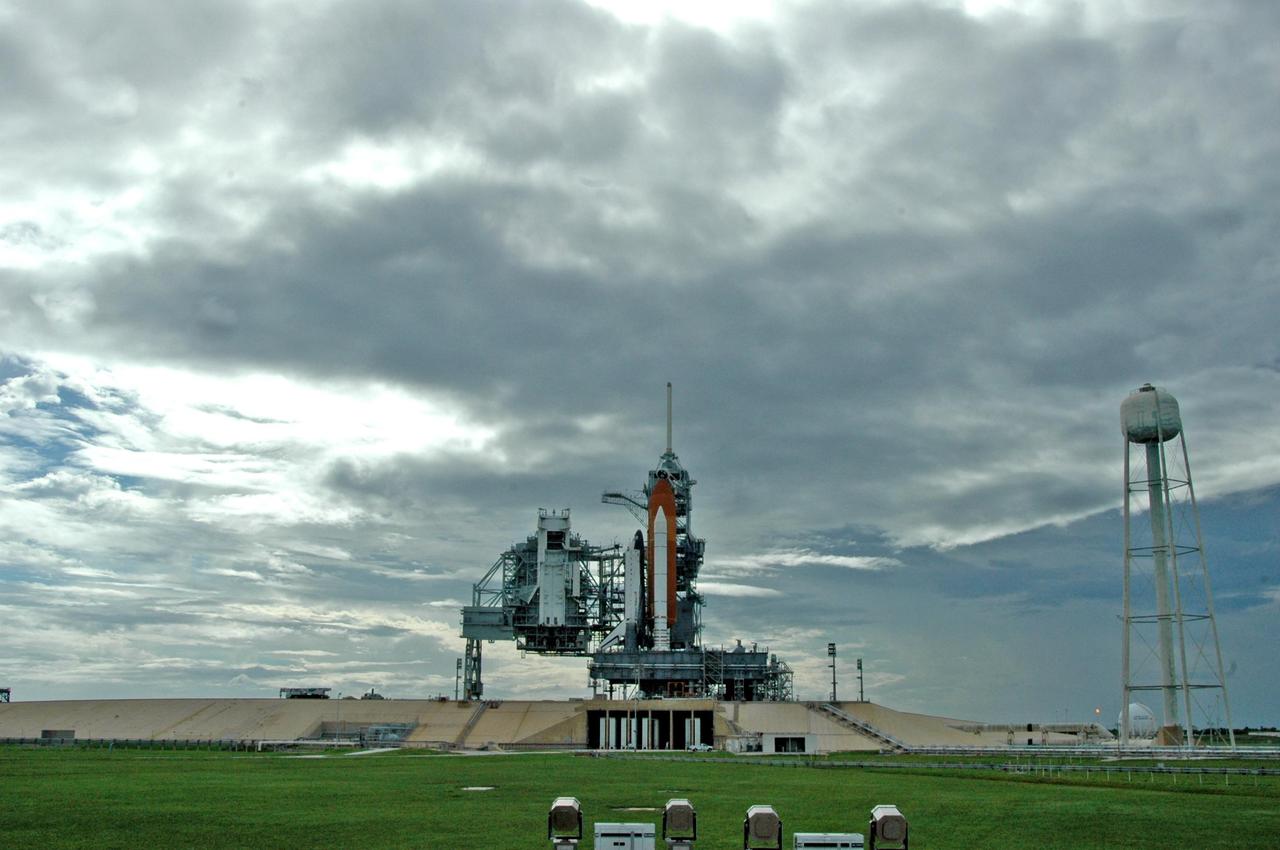 KENNEDY SPACE CENTER, FLA. -   Launch Pad 39B looks like a movie screen in this photo of Space Shuttle Atlantis after rollback of the rotating service structure.  The RSS provides protected access to the orbiter for changeout and servicing of payloads at the pad and then is rolled away before liftoff.  At right is the 300,000-gallon water tank that releases a deluge of water across the mobile launcher platform during liftoff to aid sound suppression.   Atlantis is scheduled to launch Sept. 6 at 12:29 p.m. EDT on mission STS-115.  During the mission, Atlantis' astronauts will deliver and install the 17.5-ton, bus-sized P3/P4 integrated truss segment on the station. The girder-like truss includes a set of giant solar arrays, batteries and associated electronics and will provide one-fourth of the total power-generation capability for the completed station. This mission is the 116th space shuttle flight, the 27th flight for orbiter Atlantis, and the 19th U.S. flight to the International Space Station. STS-115 is scheduled to last 11 days with a planned KSC landing at about 8:03 a.m. EDT on Sept. 17.    Photo credit: NASA/Ken Thornsley