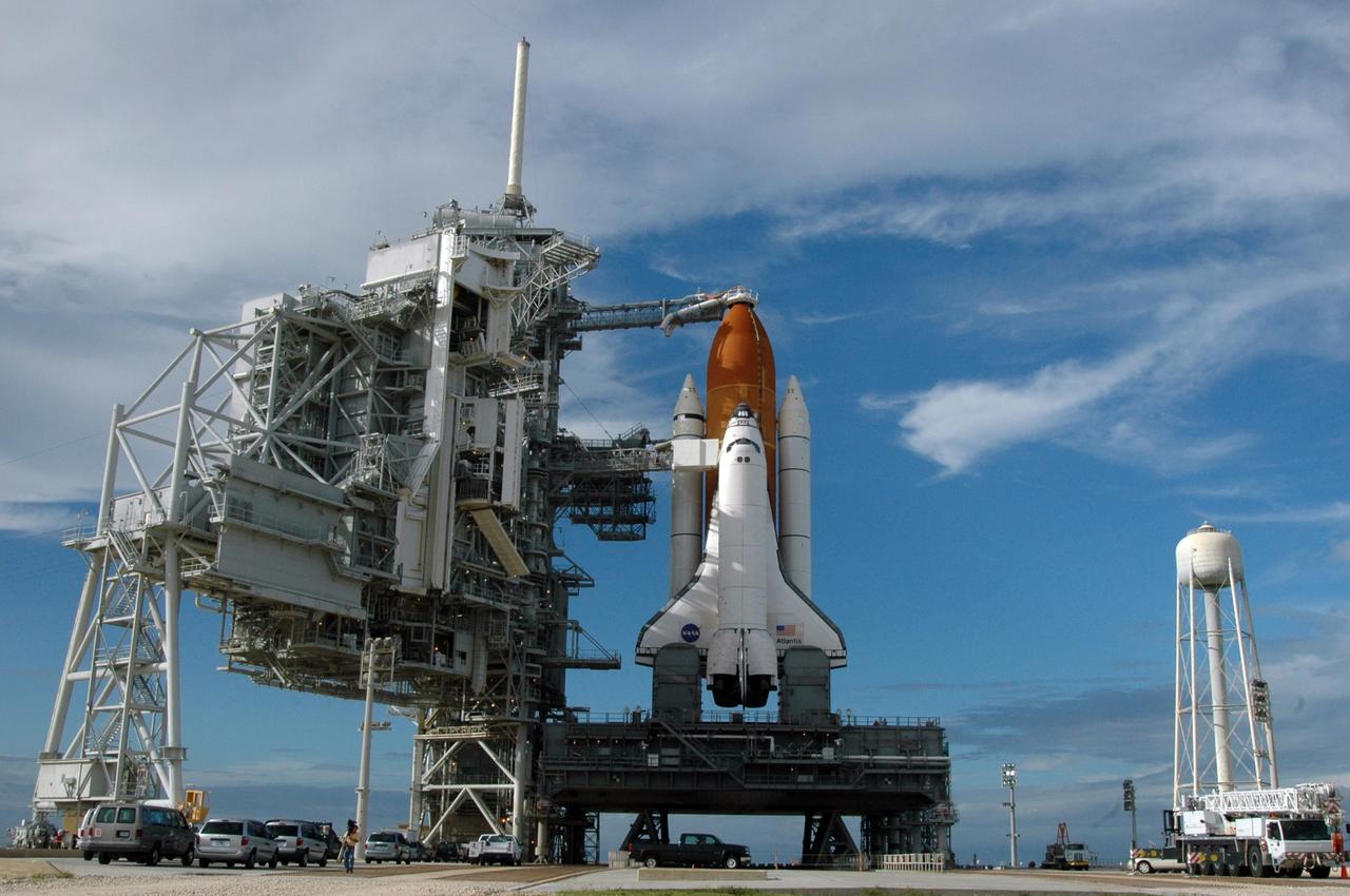 KENNEDY SPACE CENTER, FLA. - After rollback of the rotating service structure on Launch Pad 39B, Space Shuttle Atlantis shines in the late afternoon sun. The RSS provides protected access to the orbiter for changeout and servicing of payloads at the pad and then is rolled away before liftoff. At right is the 300,000-gallon water tank that releases a deluge of water across the mobile launcher platform during liftoff to aid sound suppression. Atlantis is scheduled to launch Sept. 6 at 12:29 p.m. EDT on mission STS-115. During the mission, Atlantis' astronauts will deliver and install the 17.5-ton, bus-sized P3/P4 integrated truss segment on the station. The girder-like truss includes a set of giant solar arrays, batteries and associated electronics and will provide one-fourth of the total power-generation capability for the completed station. This mission is the 116th space shuttle flight, the 27th flight for orbiter Atlantis, and the 19th U.S. flight to the International Space Station. STS-115 is scheduled to last 11 days with a planned KSC landing at about 8:03 a.m. EDT on Sept. 17. Photo credit: NASA/Ken Thornsley