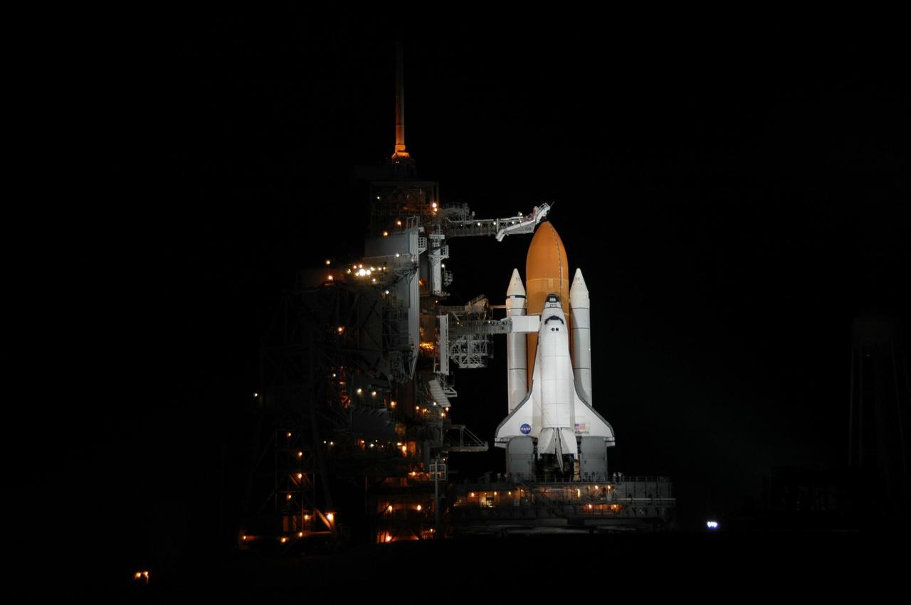 KENNEDY SPACE CENTER, FLA. -   Space Shuttle Atlantis is bathed in light on Launch Pad 39B. Atlantis was originally scheduled to launch at 12:29 p.m. EDT on this date, but  a 24-hour scrub was called by mission managers due to a concern with Fuel Cell 1.  Seen poised above the orange external tank is the vent hood (known as the "beanie cap") at the end of the gaseous oxygen vent arm. Vapors are created as the liquid oxygen in the external tank boil off. The hood vents the gaseous oxygen vapors away from the space shuttle vehicle.  During the STS-115 mission, Atlantis' astronauts will deliver and install the 17.5-ton, bus-sized P3/P4 integrated truss segment on the station. The girder-like truss includes a set of giant solar arrays, batteries and associated electronics and will provide one-fourth of the total power-generation capability for the completed station. This mission is the 116th space shuttle flight, the 27th flight for orbiter Atlantis, and the 19th U.S. flight to the International Space Station. STS-115 is scheduled to last 11 days with a planned landing at KSC.   Photo credit: NASA/Jim Grossmann