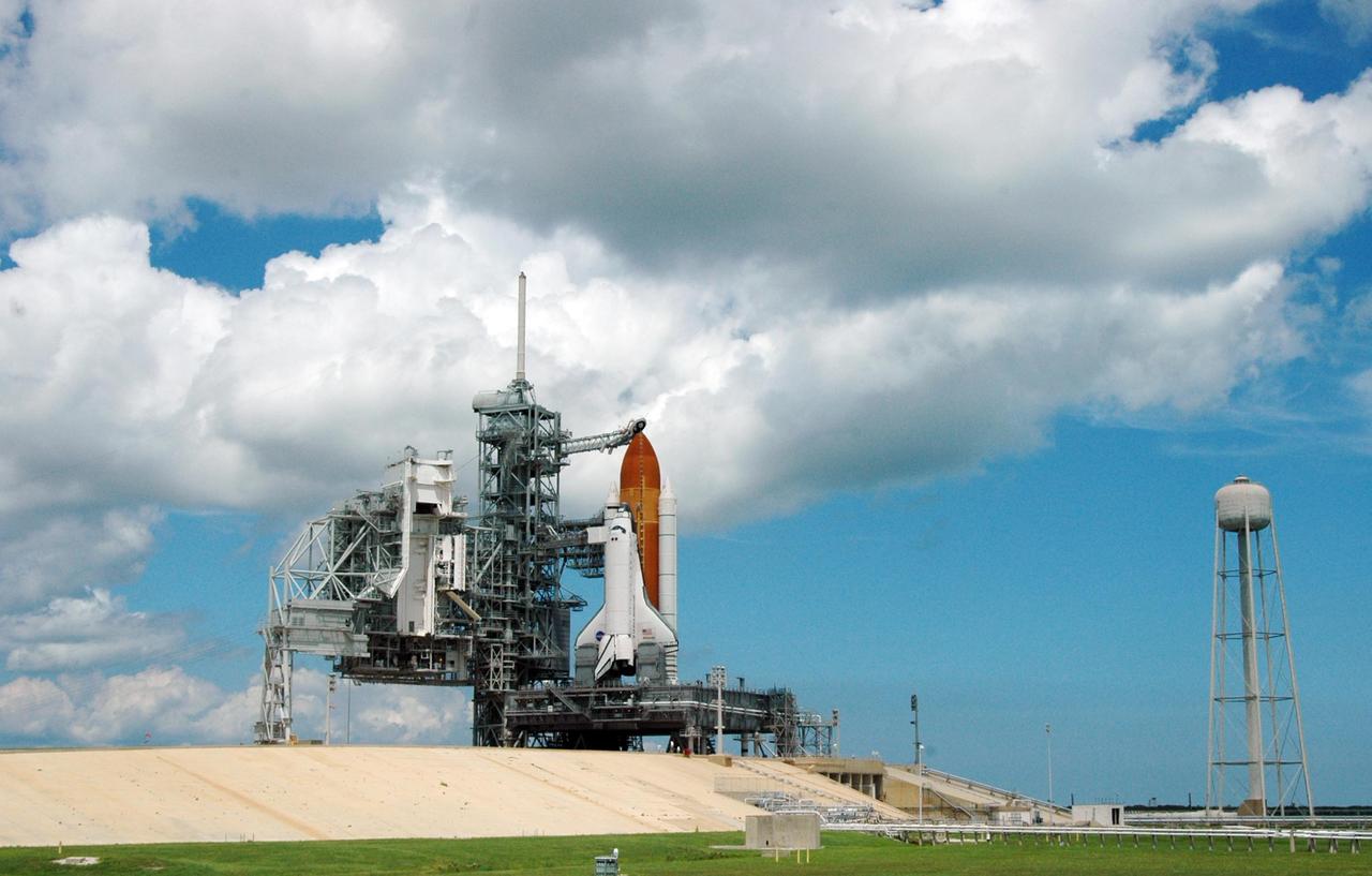 KENNEDY SPACE CENTER, FLA. -   Huge clouds roll over Launch Pad 39B where Space Shuttle Atlantis still sits after the scrub of its launch on mission STS-115.  Atlantis was originally scheduled to launch at 12:29 p.m. EDT on this date, but  a 24-hour scrub was called by mission managers due to a concern with fuel cell 1.  Towering above the shuttle is the 80-foot lightning mast.  At right is the 300,000-gallon water tank that releases its contents onto the mobile launcher platform during liftoff to aid sound suppression.   During the STS-115 mission, Atlantis' astronauts will deliver and install the 17.5-ton, bus-sized P3/P4 integrated truss segment on the station. The girder-like truss includes a set of giant solar arrays, batteries and associated electronics and will provide one-fourth of the total power-generation capability for the completed station. This mission is the 116th space shuttle flight, the 27th flight for orbiter Atlantis, and the 19th U.S. flight to the International Space Station. STS-115 is scheduled to last 11 days with a planned landing at KSC.   Photo credit: NASA/Ken Thornsley