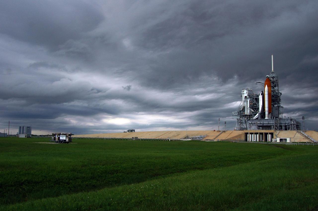 KENNEDY SPACE CENTER, FLA. -  Storm clouds roll across Launch Pad 39B where Space Shuttle Atlantis still sits on the pad.    Atlantis was originally scheduled to launch Aug. 27, but  a scrub was called by mission managers due to a concern with fuel cell 1.  Towering above the shuttle is the 80-foot lightning mast. During the STS-115 mission, Atlantis' astronauts will deliver and install the 17.5-ton, bus-sized P3/P4 integrated truss segment on the station. The girder-like truss includes a set of giant solar arrays, batteries and associated electronics and will provide one-fourth of the total power-generation capability for the completed station. This mission is the 116th space shuttle flight, the 27th flight for orbiter Atlantis, and the 19th U.S. flight to the International Space Station. STS-115 is scheduled to last 11 days with a planned landing at KSC.   Photo credit: NASA/Ken Thornsley