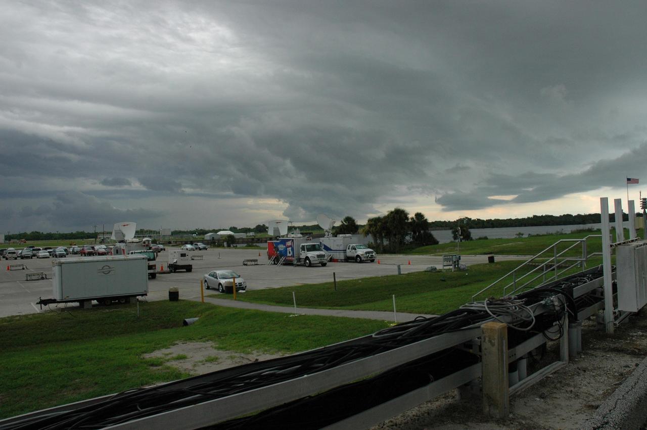 KENNEDY SPACE CENTER, FLA. -  Menacing storm clouds roll through the Launch Complex 39 Area at NASA's Kennedy Space Center.  Seen in the photo is the lower parking lot for the NASA News Center where the media's vehicles and satellite trucks are situated the day before (L-1) the second scheduled launch attempt for Space Shuttle Atlantis on mission STS-115.  During the STS-115 mission, Atlantis' astronauts will deliver and install the 17.5-ton, bus-sized P3/P4 integrated truss segment on the station. The girder-like truss includes a set of giant solar arrays, batteries and associated electronics and will provide one-fourth of the total power-generation capability for the completed station. This mission is the 116th space shuttle flight, the 27th flight for orbiter Atlantis, and the 19th U.S. flight to the International Space Station. STS-115 is scheduled to last 11 days with a planned landing at KSC.   Photo credit: NASA/Troy Cryder