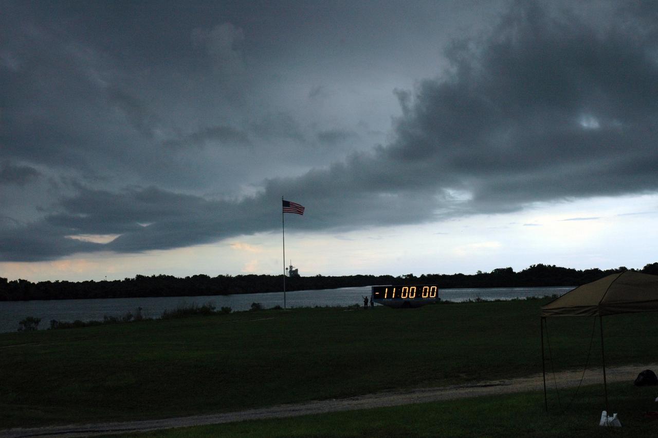 KENNEDY SPACE CENTER, FLA. -  Menacing storm clouds roll  through the Launch Complex 39 Area at NASA's Kennedy Space Center.  Framed between the horizon and the clouds is Space Shuttle Atlantis on Launch Pad 39B.  The flag in the foreground is at the NASA News Center, near the countdown clock.  During the STS-115 mission, Atlantis' astronauts will deliver and install the 17.5-ton, bus-sized P3/P4 integrated truss segment on the station. The girder-like truss includes a set of giant solar arrays, batteries and associated electronics and will provide one-fourth of the total power-generation capability for the completed station. This mission is the 116th space shuttle flight, the 27th flight for orbiter Atlantis, and the 19th U.S. flight to the International Space Station. STS-115 is scheduled to last 11 days with a planned landing at KSC.   Photo credit: NASA/Troy Cryder