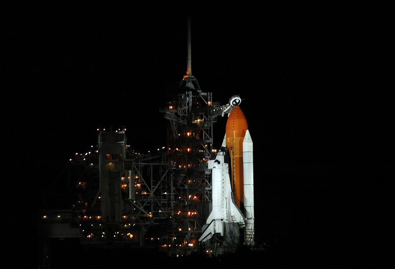 KENNEDY SPACE CENTER, FLA. - Space Shuttle Atlantis is illuminated on Launch Pad 39B, surrounded by amber lights on the rotating and fixed service structures. Seen above the golden external tank is the vent hood (known as the "beanie cap") at the end of the gaseous oxygen vent arm. Vapors are created as the liquid oxygen in the external tank boil off. The hood vents the gaseous oxygen vapors away from the space shuttle vehicle. Atlantis was originally scheduled to launch on Aug. 27, but a scrub was called by mission managers due to a concern with fuel cell 1. Atlantis is scheduled to lift off at 11:41 a.m. EDT Sept. 8. During the STS-115 mission, Atlantis' astronauts will deliver and install the 17.5-ton, bus-sized P3/P4 integrated truss segment on the station. The girder-like truss includes a set of giant solar arrays, batteries and associated electronics and will provide one-fourth of the total power-generation capability for the completed station. This mission is the 116th space shuttle flight, the 27th flight for orbiter Atlantis, and the 19th U.S. flight to the ISS. STS-115 is scheduled to last 11 days with a planned landing at KSC. Photo credit: NASA/Ken Thornsley