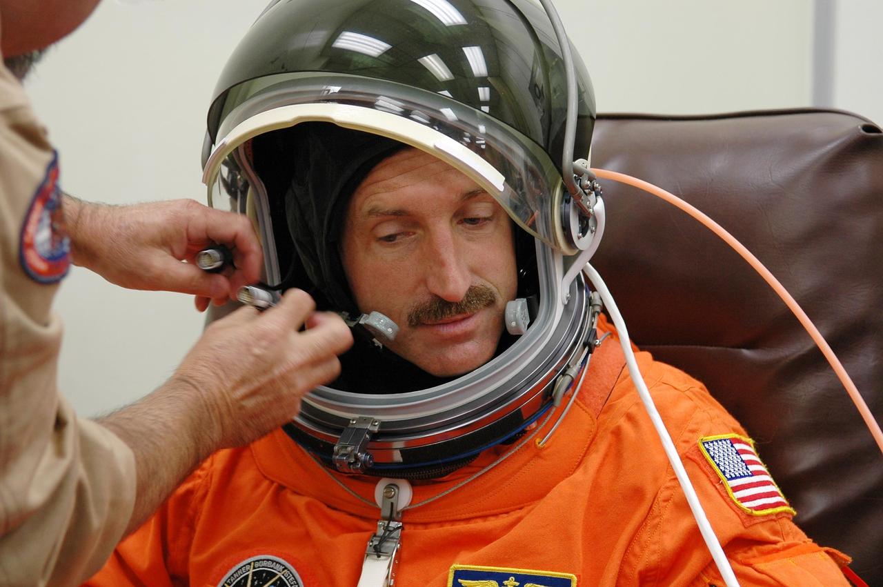 KENNEDY SPACE CENTER, FLA. -  In the Operations and Checkout Building at NASA Kennedy Space Center, STS-115 Mission Specialist Daniel Burbank gets a final adjustment on his helmet before heading to the launch pad for another attempt at liftoff.  The launch attempt on Sept. 8 was scrubbed due to an issue with a fuel cut-off sensor system inside the external fuel tank. This is one of several systems that protect the shuttle's main engines by triggering their shutdown if fuel runs unexpectedly low.  During the STS-115 mission, Atlantis' astronauts will deliver and install the 17.5-ton, bus-sized P3/P4 integrated truss segment on the station. The girder-like truss includes a set of giant solar arrays, batteries and associated electronics and will provide one-fourth of the total power-generation capability for the completed station. This mission is the 116th space shuttle flight, the 27th flight for orbiter Atlantis, and the 19th U.S. flight to the ISS. STS-115 is scheduled to last 11 days with a planned landing at KSC.  Photo credit: NASA/Kim Shiflett