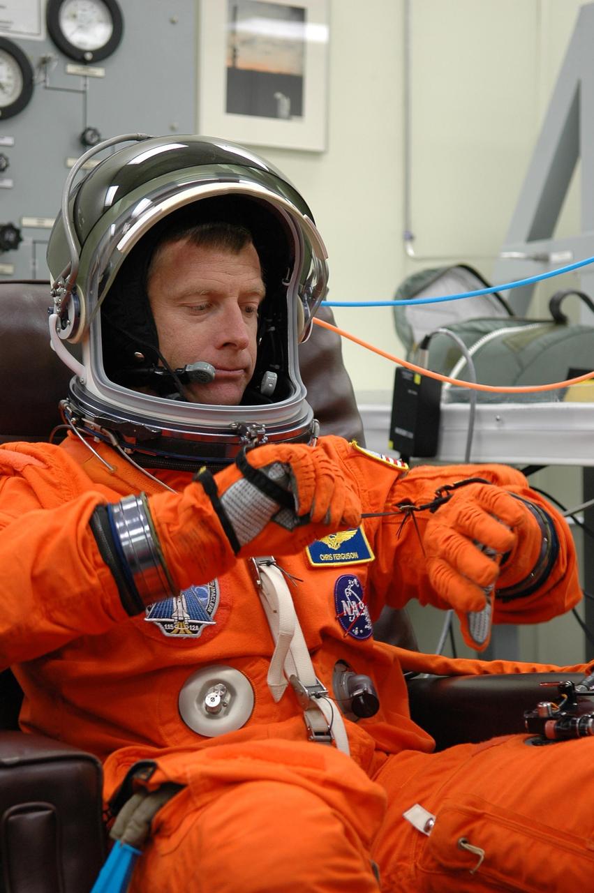 KENNEDY SPACE CENTER, FLA. - In the Operations and Checkout Building at NASA Kennedy Space Center, STS-115 Pilot Christopher Ferguson adjusts his glove during suitup before heading to the launch pad for another attempt at liftoff.  The launch attempt on Sept. 8 was scrubbed due to an issue with a fuel cut-off sensor system inside the external fuel tank. This is one of several systems that protect the shuttle's main engines by triggering their shutdown if fuel runs unexpectedly low.  During the STS-115 mission, Atlantis' astronauts will deliver and install the 17.5-ton, bus-sized P3/P4 integrated truss segment on the station. The girder-like truss includes a set of giant solar arrays, batteries and associated electronics and will provide one-fourth of the total power-generation capability for the completed station. This mission is the 116th space shuttle flight, the 27th flight for orbiter Atlantis, and the 19th U.S. flight to the ISS. STS-115 is scheduled to last 11 days with a planned landing at KSC.  Photo credit: NASA/Kim Shiflett