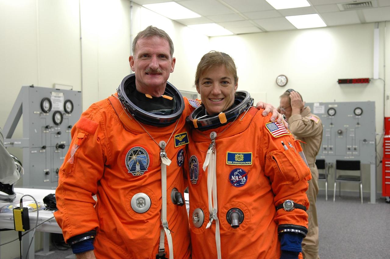 KENNEDY SPACE CENTER, FLA. -  In the Operations and Checkout Building at NASA Kennedy Space Center, STS-115 Mission Specialists Joseph Tanner and Heidemarie Stefanyshyn-Piper pose while suiting up for the ride to Launch Pad 39B and another attempt at liftoff.  The launch attempt on Sept. 8 was scrubbed due to an issue with a fuel cut-off sensor system inside the external fuel tank. This is one of several systems that protect the shuttle's main engines by triggering their shutdown if fuel runs unexpectedly low.  During the STS-115 mission, Atlantis' astronauts will deliver and install the 17.5-ton, bus-sized P3/P4 integrated truss segment on the station. The girder-like truss includes a set of giant solar arrays, batteries and associated electronics and will provide one-fourth of the total power-generation capability for the completed station. This mission is the 116th space shuttle flight, the 27th flight for orbiter Atlantis, and the 19th U.S. flight to the ISS. STS-115 is scheduled to last 11 days with a planned landing at KSC.  Photo credit: NASA/Kim Shiflett