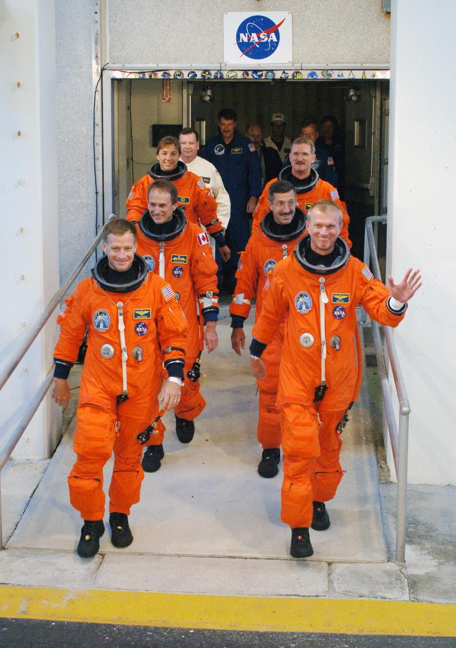 KENNEDY SPACE CENTER, FLA. - After suiting up, the STS-115 mission crew exits the Operations and Checkout Building to board the Astrovan to Launch Pad 39B.  On the left, front to back, are Pilot Christopher Ferguson and Mission Specialists Steven MacLean and Heidemarie Stefanyshyn-Piper.  On the right, front to back, are Commander Brent Jett and Mission Specialists Daniel Burbank and Joseph Tanner.  The launch attempt on Sept. 8 was scrubbed due to an issue with a fuel cut-off sensor system inside the external fuel tank. This is one of several systems that protect the shuttle's main engines by triggering their shutdown if fuel runs unexpectedly low.  During the STS-115 mission, Atlantis' astronauts will deliver and install the 17.5-ton, bus-sized P3/P4 integrated truss segment on the station. The girder-like truss includes a set of giant solar arrays, batteries and associated electronics and will provide one-fourth of the total power-generation capability for the completed station. This mission is the 116th space shuttle flight, the 27th flight for orbiter Atlantis, and the 19th U.S. flight to the ISS. STS-115 is scheduled to last 11 days with a planned landing at KSC.  Photo credit: NASA/Kim Shiflett