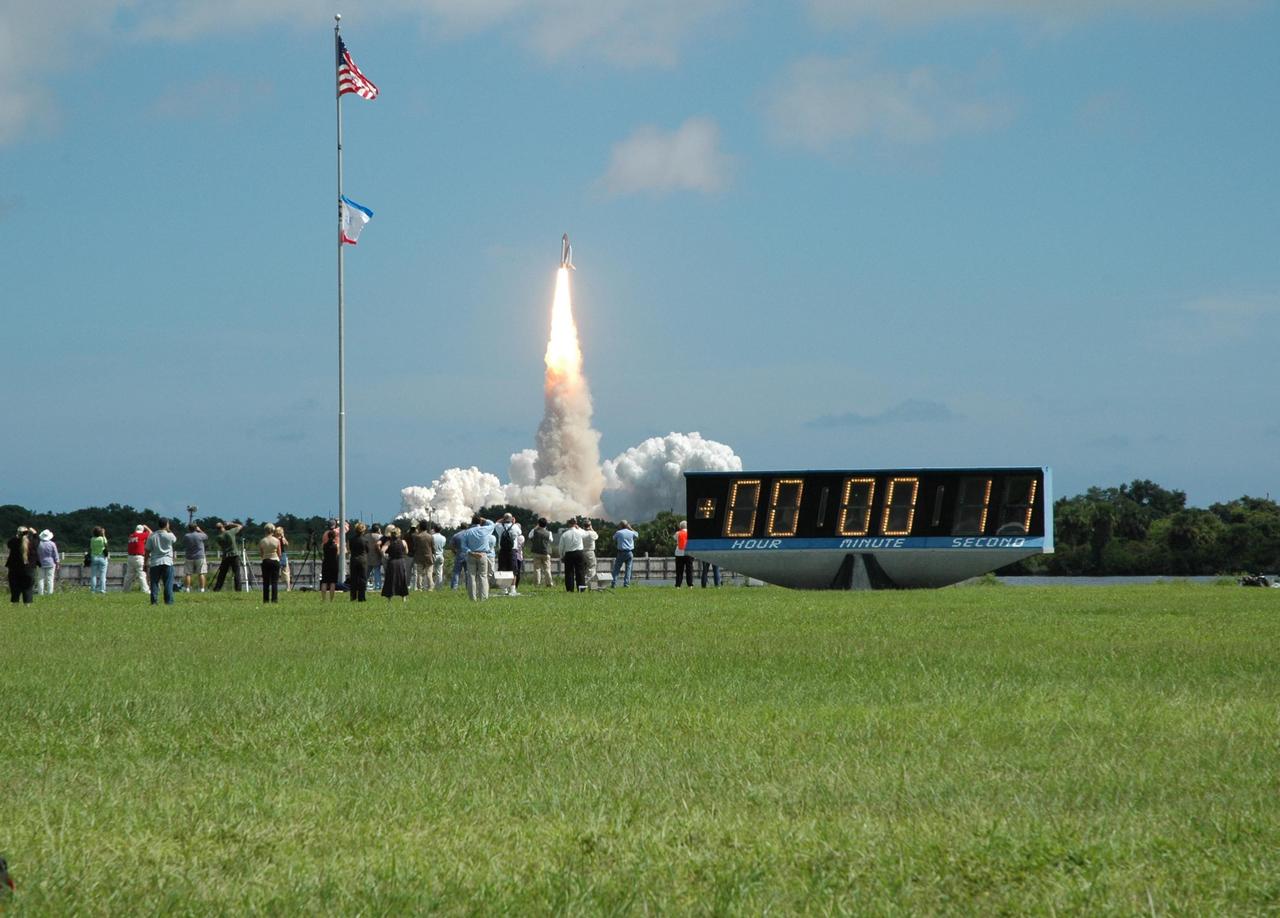KENNEDY SPACE CENTER, FLA. - Space Shuttle Atlantis roars off the launch pad for a rendezvous with the International Space Station on mission STS-115.  In the foreground is the countdown clock, marking launch and mission-elapsed time, on the grounds of the NASA News Center. After launch attempts were scrubbed Aug. 27 and 29 and Sept. 3 and 8 due to weather and technical concerns,  this launch was executed perfectly.  During the STS-115 mission, Atlantis' astronauts will deliver and install the 17.5-ton, bus-sized P3/P4 integrated truss segment on the station. The girder-like truss includes a set of giant solar arrays, batteries and associated electronics and will provide one-fourth of the total power-generation capability for the completed station. This mission is the 116th space shuttle flight, the 27th flight for orbiter Atlantis, and the 19th U.S. flight to the ISS. STS-115 is scheduled to last 11 days with a planned landing at KSC.  Photo credit: NASA/Webb Dillard