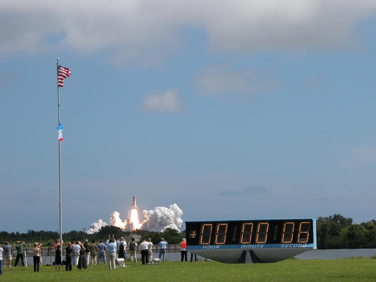 KENNEDY SPACE CENTER, FLA. - With applause and cheers from the onlookers, Space Shuttle Atlantis roars off the launch pad for a rendezvous with the International Space Station on mission STS-115.  In the foreground is the countdown clock, marking launch and mission-elapsed time, on the grounds of the NASA News Center. After launch attempts were scrubbed Aug. 27 and 29 and Sept. 3 and 8 due to weather and technical concerns,  this launch was executed perfectly.  During the STS-115 mission, Atlantis' astronauts will deliver and install the 17.5-ton, bus-sized P3/P4 integrated truss segment on the station. The girder-like truss includes a set of giant solar arrays, batteries and associated electronics and will provide one-fourth of the total power-generation capability for the completed station. This mission is the 116th space shuttle flight, the 27th flight for orbiter Atlantis, and the 19th U.S. flight to the ISS. STS-115 is scheduled to last 11 days with a planned landing at KSC.  Photo credit: NASA/Debbie Odom