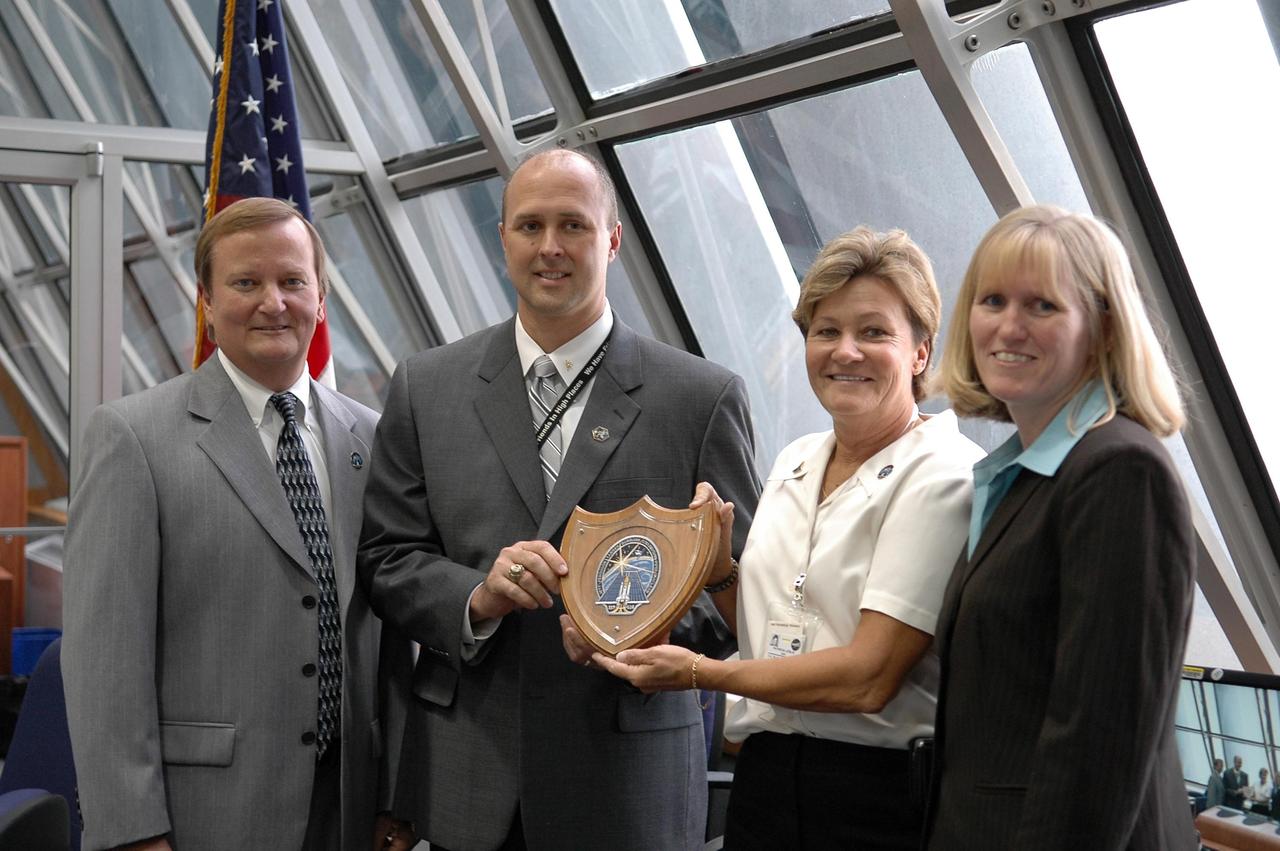 KENNEDY SPACE CENTER, FLA. -  Inside the Launch Control Center, Robbie Ashley, STS-115 payload manager,  and Pat Lesley, with United Space Alliance, receive a special award from (at left) Shuttle Launch Director Mike Leinbach and (at right) NASA Flow Director Angie Brewer.  Mission STS-115 is the 116th space shuttle flight, the 27th flight for orbiter Atlantis, and the 19th U.S. flight to the International Space Station. STS-115 is scheduled to last 11 days with a planned landing at KSC. Photo credit: NASA/Kim Shiflett