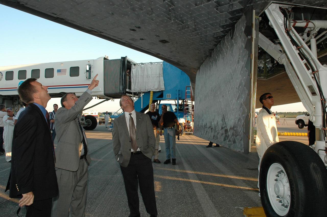 KENNEDY SPACE CENTER, FLA. - Before welcoming the STS-115 crew on their return from space, NASA officials look at the underside of the orbiter Atlantis on the Shuttle Landing Facility.  From left are Mission Launch Integration Director LeRoy Cain, NASA Administrator Michael Griffin and Shuttle Launch Director Mike Leinbach.  During the mission, astronauts completed three spacewalks to attach the P3/P4 integrated truss structure to the International Space Station.  Main gear touchdown was at 6:21:30 a.m. EDT.  Nose gear touchdown was at 6:21:36 a.m. and wheel stop was at 6:22:16 a.m. At touchdown -- nominally about 2,500 ft. beyond the runway threshold -- the orbiter is traveling at a speed ranging from 213 to 226 mph. Atlantis traveled 4.9 million miles, landing on orbit 187. Mission elapsed time was 11 days, 19 hours, six minutes. This is the 15th night landing at KSC and the 23rd night landing overall.  Photo credit: NASA/Kim Shiflett