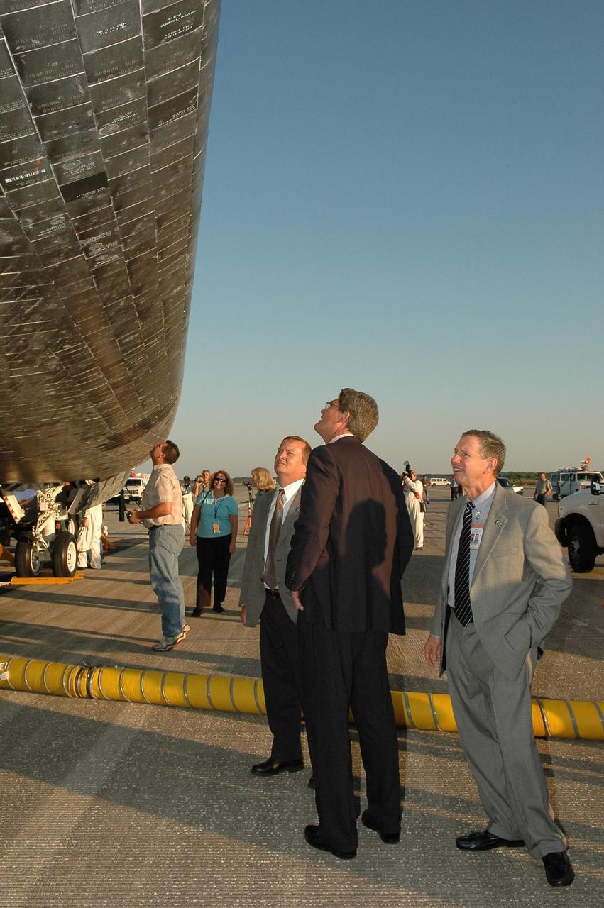 KENNEDY SPACE CENTER, FLA. - Before welcoming the STS-115 crew on their return from space, NASA officials look at the underside of the orbiter Atlantis on the Shuttle Landing Facility.  From right are  NASA Administrator Michael Griffin, KSC Deputy Director Bill Parsons and Shuttle Launch Director Mike Leinbach.   During the mission, astronauts completed three spacewalks to attach the P3/P4 integrated truss structure to the International Space Station.  Main gear touchdown was at 6:21:30 a.m. EDT.  Nose gear touchdown was at 6:21:36 a.m. and wheel stop was at 6:22:16 a.m. At touchdown -- nominally about 2,500 ft. beyond the runway threshold -- the orbiter is traveling at a speed ranging from 213 to 226 mph. Atlantis traveled 4.9 million miles, landing on orbit 187. Mission elapsed time was 11 days, 19 hours, six minutes. This is the 15th night landing at KSC and the 23rd night landing overall.  Photo credit: NASA/Kim Shiflett