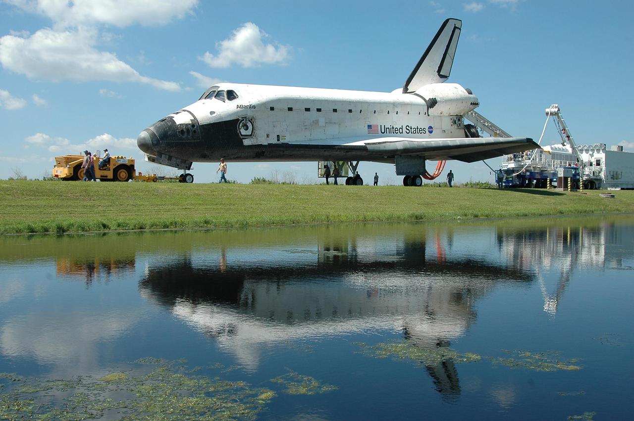 KENNEDY SPACE CENTER, FLA. -  The movement of Atlantis is reflected in the water next to the tow-way as the orbiter is towed from the Shuttle Landing Facility to the Orbiter Processing Facility.  Umbilical lines are still attached to the orbiter. Atlantis landed on Runway 33 at 6:21:30 a.m. EDT after the 11-day, 19-hour, 6-minute mission STS-115 to the International Space Station.  Atlantis traveled 4.9 million miles, landing on orbit 187. During the mission, astronauts delivered and installed the massive P3/P4 truss, an integral part of the station's backbone, and two sets of solar arrays that will eventually provide one quarter of the station's power. In the OPF, the process flow will begin to ready the vehicle for its next flight.  Photo credit: NASA/Kim Shiflett