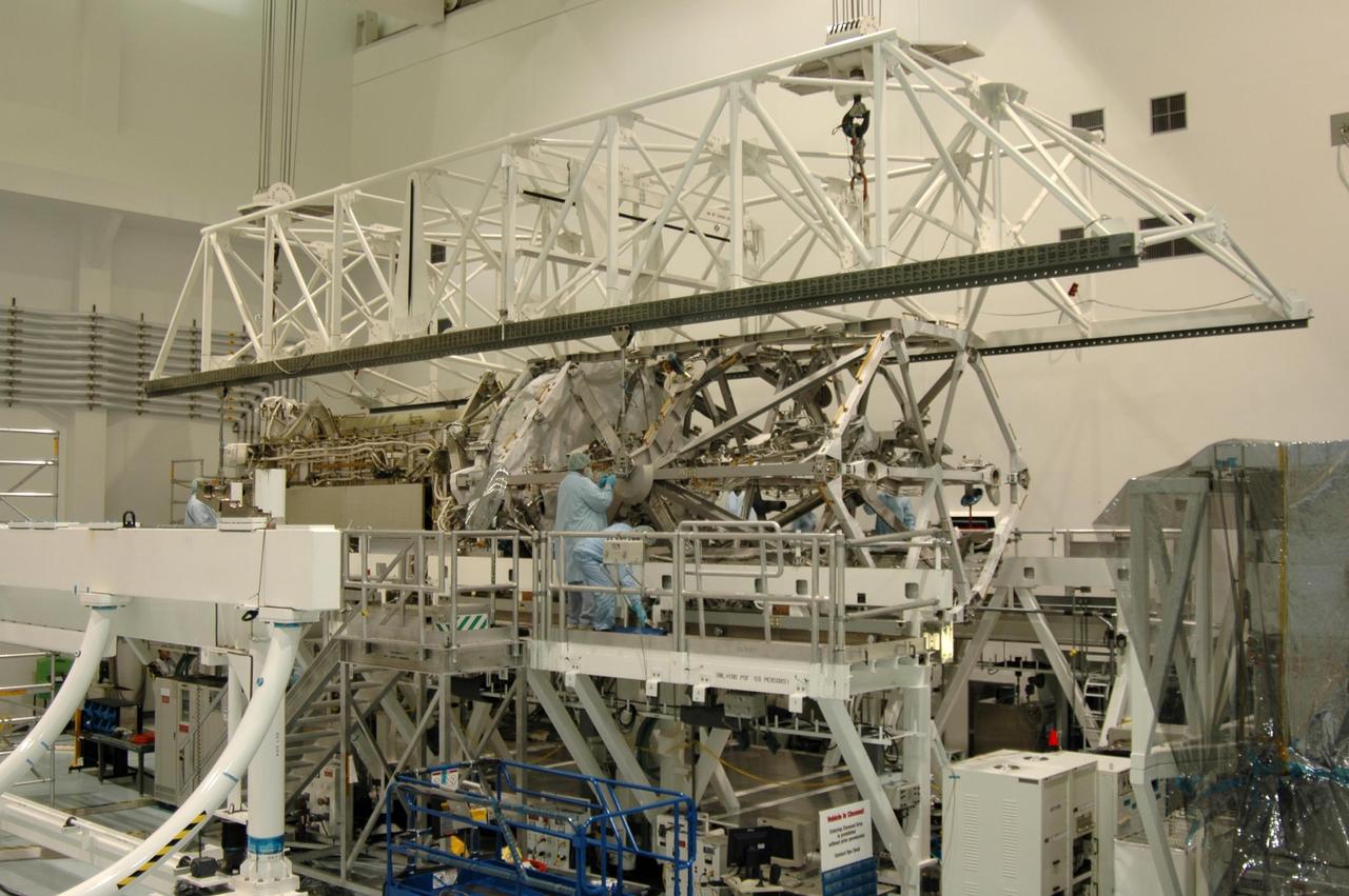 KENNEDY SPACE CENTER, FLA. - In the Space Station Processing Facility, an overhead crane lowers the S3/S4 integrated truss structure onto a work stand. It was moved from a rotation stand at left. Along with a third set of solar arrays and batteries, the truss is scheduled to fly on mission STS-117 aboard Space Shuttle Atlantis to the International Space Station. The crew of six astronauts will install the truss to continue assembly of the station. Photo credit: NASA/Dimitri Gerondidakis