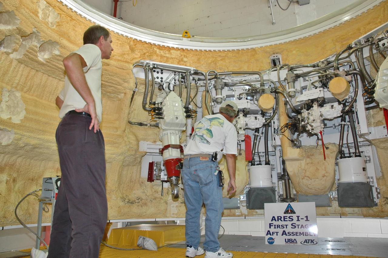 KENNEDY SPACE CENTER, FLA. -  In the Assembly and Refurbishment Facility at NASA's Kennedy Space Center, workers examine some of the hardware inside the solid rocket booster aft skirt designated for use on the first stage of the ARES I-1 launch vehicle in its first test flight.  Ares I is the vehicle being developed for launch of the crew exploration vehicle (CEV), named Orion. Ares I-1 is currently targeted for launch from Launch Pad 39B in 2009 using the SRB first stage and a simulated second stage and simulated CEV. Ares I ascent tests and Ares I orbital tests will also take place at Kennedy at later dates.  Photo credit: NASA/Jack Pfaller