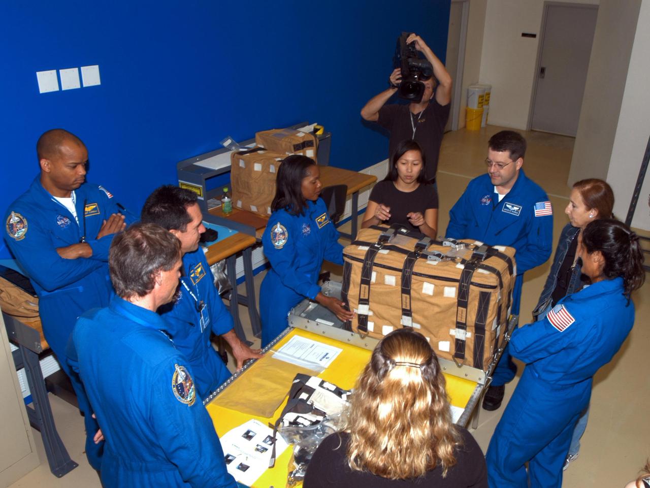 KENNEDY SPACE CENTER, FLA. - Members of the STS-116 crew examine components of the mission payload at SPACEHAB in Cape Canaveral, Fla. Clockwise from lower left (in their blue uniforms) around the table are Mission Specialist Christer Fuglesang , Pilot William Oefelein, and Mission Specialists Joan Higginbotham, Nicholas Patrick and Sunita Williams. At far left is Robert Curbeam. The Swedish Fuglesang represents the European Space Agency. On the table is a stowage bag. Next to Patrick at right is astronaut Marsha Ivins, currently assigned to the Astronaut Office, Space Station/Shuttle Branches for crew equipment, habitability and stowage. Mission crews make frequent trips to the Space Coast to become familiar with the equipment and payloads they will be using. STS-116 will be mission number 20 to the International Space Station and construction flight 12A.1. The mission payload is the SPACEHAB module, the P5 integrated truss structure and other key components. Launch is scheduled for no earlier than Dec. 7. Photo credit: NASA/George Shelton