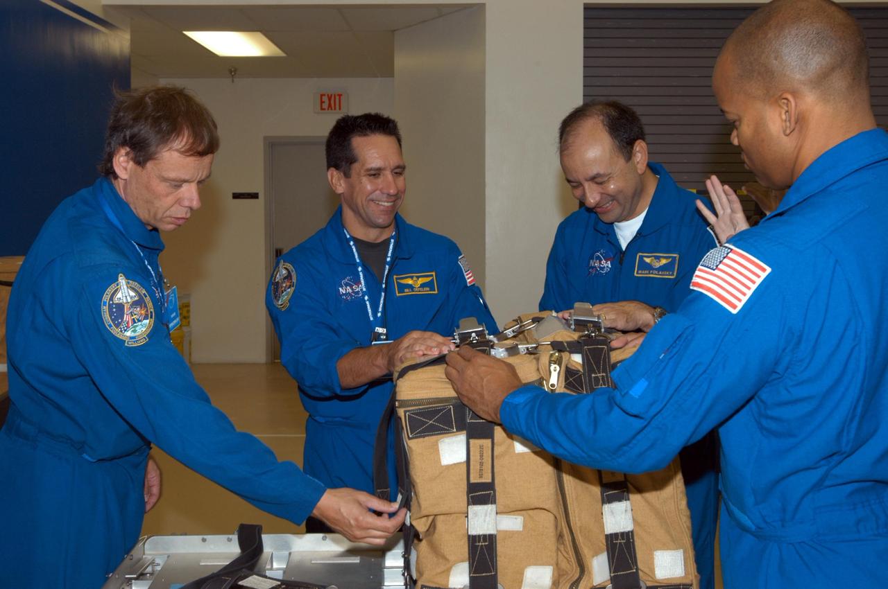 KENNEDY SPACE CENTER, FLA. -  Members of the STS-116 crew examine components of the mission payload at SPACEHAB in Cape Canaveral, Fla.    From left are Mission Specialist Christer Fuglesang , Pilot William Oefelein, Commander Mark Polansky and Mission Specialist Robert Curbeam, who practice opening and closing a  stowage bag.  Fuglesang, from Sweden,  represents the European Space Agency.   Mission crews make frequent trips to the Space Coast to become familiar with the equipment and payloads they will be using.  STS-116 will be mission number 20 to the International Space Station and construction flight 12A.1.  The mission payload is the SPACEHAB module, the P5 integrated truss structure and other key components.   Launch is scheduled for no earlier than Dec. 7.  Photo credit: NASA/George Shelton
