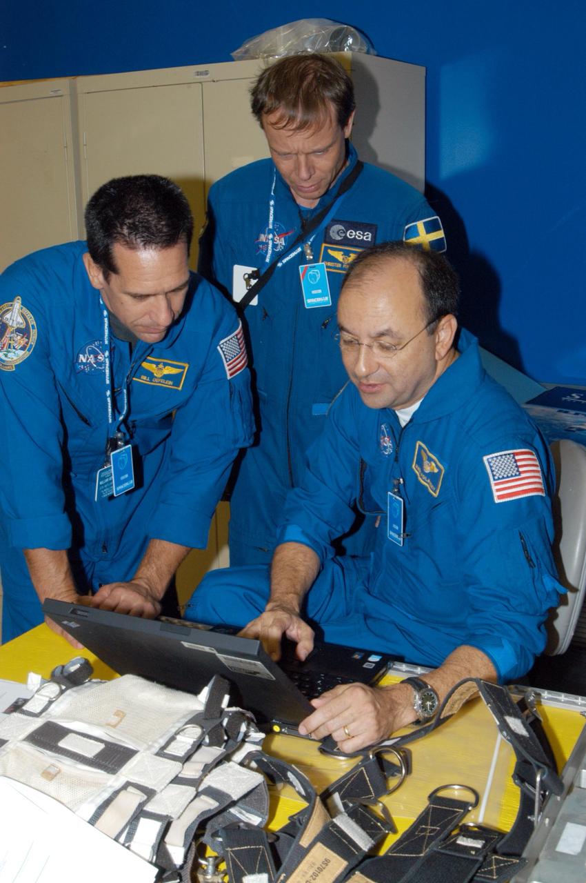 KENNEDY SPACE CENTER, FLA. - At SPACEHAB in Cape Canaveral, Fla., STS-116 Pilot William Oefelein, Mission Specialist Christer Fuglesang and Commander Mark Polansky check data on a computer while examining the rack front stowage trays that are used inside the SPACEHAB module. Mission crews make frequent trips to the Space Coast to become familiar with the equipment and payloads they will be using. STS-116 will be mission number 20 to the International Space Station and construction flight 12A.1. The mission payload is the SPACEHAB module, the P5 integrated truss structure and other key components. Launch is scheduled for no earlier than Dec. 7. Photo credit: NASA/George Shelton