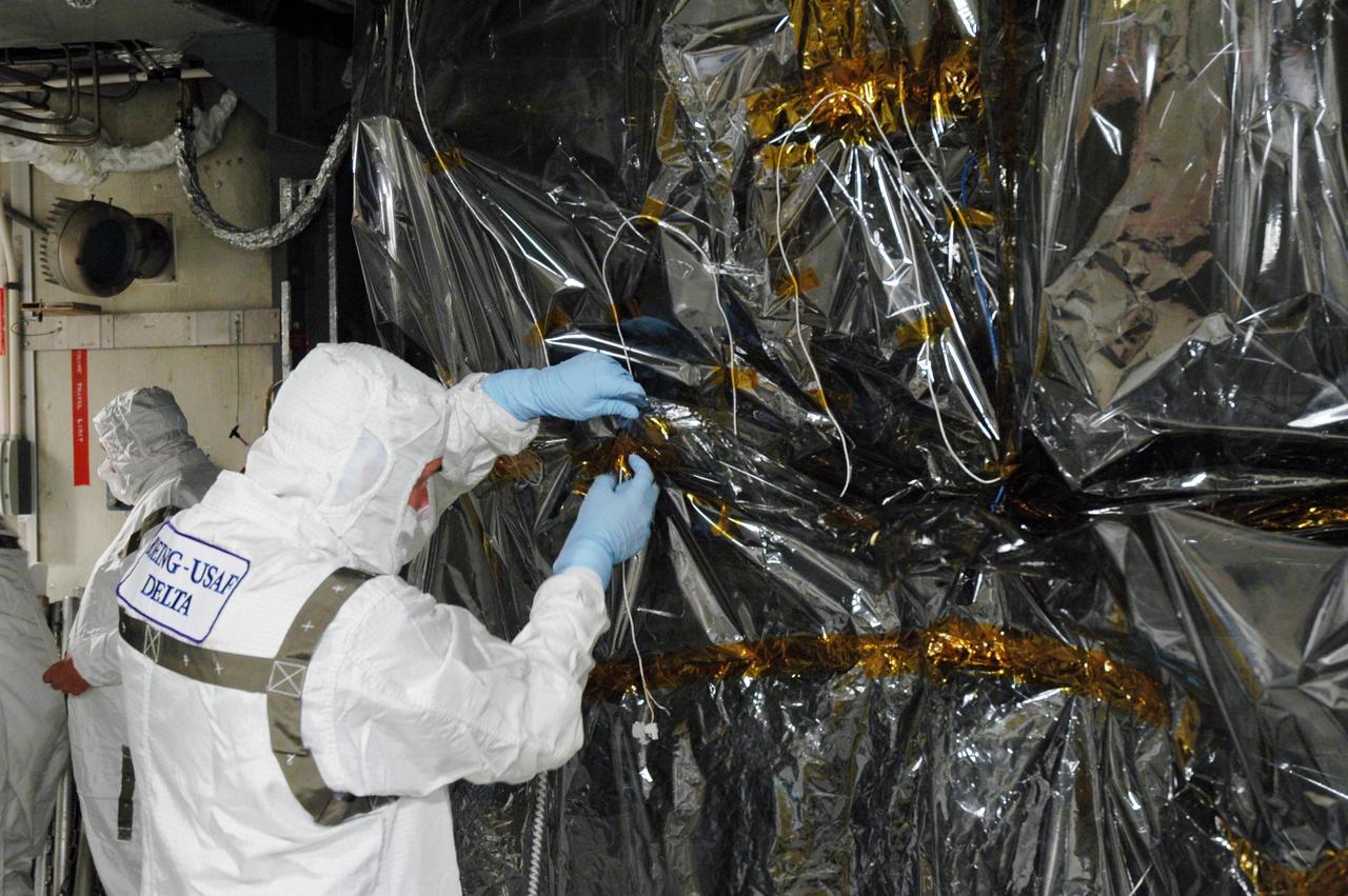 KENNEDY SPACE CENTER, FLA. - Inside the mobile service tower on Launch Pad 17-B at Cape Canaveral Air Force Station, workers begin removing the protective cover surrounding the STEREO spacecraft. The spacecraft is being prepared for launch, scheduled for Oct. 25. STEREO stands for Solar Terrestrial Relations Observatory and comprises two spacecraft that will launch in a piggyback mode, separating after reaching the appropriate orbit. The STEREO mission is the first to take measurements of the sun and solar wind in 3-dimension. This new view will improve our understanding of space weather and its impact on the Earth. The STEREO mission is managed by Goddard. The Applied Physics Laboratory designed and built the spacecraft. The laboratory will maintain command and control of the observatories throughout the mission, while NASA tracks and receives the data, determines the orbit of the satellites, and coordinates the science results. Photo credit: NASA/Jim Grossmann