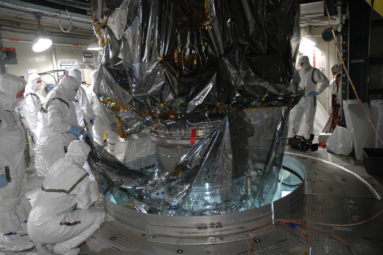 KENNEDY SPACE CENTER, FLA. - Inside the mobile service tower on Launch Pad 17-B at Cape Canaveral Air Force Station, workers begin removing the protective cover surrounding the STEREO spacecraft. The spacecraft is being prepared for launch, scheduled for Oct. 25. STEREO stands for Solar Terrestrial Relations Observatory and comprises two spacecraft that will launch in a piggyback mode, separating after reaching the appropriate orbit. The STEREO mission is the first to take measurements of the sun and solar wind in 3-dimension. This new view will improve our understanding of space weather and its impact on the Earth. The STEREO mission is managed by Goddard. The Applied Physics Laboratory designed and built the spacecraft. The laboratory will maintain command and control of the observatories throughout the mission, while NASA tracks and receives the data, determines the orbit of the satellites, and coordinates the science results. Photo credit: NASA/Jim Grossmann