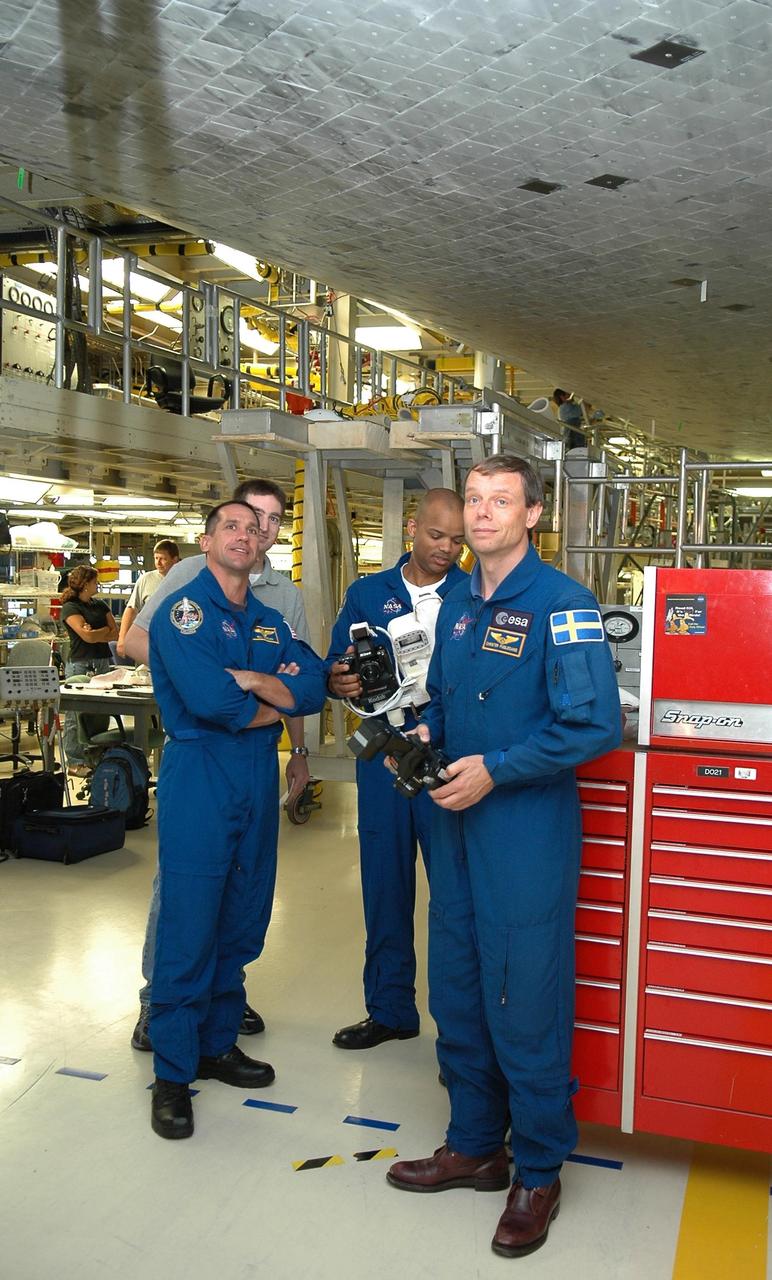 KENNEDY SPACE CENTER, FLA. -  In the Orbiter Processing Facility, STS-116 Pilot William Oefelein (left) gets a close look at the underside of the orbiter Discovery.  At right, Mission Specialists Robert Curbeam and Christer Fugelsang are practicing with cameras similar to those the crew will use on the mission.  Fugelsang represents the European Space Agency. The crew is at KSC for a Crew Equipment Interface Test.   Mission crews make frequent trips to the Kennedy Space Center to become familiar with the equipment and payloads they will be using.  STS-116 will be mission No. 20 to the International Space Station and construction flight 12A.1.  The mission payload is the SPACEHAB module, the P5 integrated truss structure and other key components.   Launch is scheduled for no earlier than Dec. 7.  Photo credit: NASA/Kim Shiflett