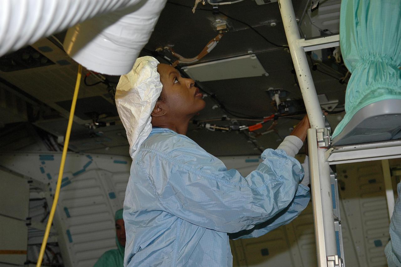 KENNEDY SPACE CENTER, FLA. -   In the Orbiter Processing Facility, STS-116 Mission Specialist Joan Higginbotham gets a close look at equipment in the orbiter Discovery’s mid-deck.  She and other crew members are taking part in a Crew Equipment Interface Test (CEIT). A CEIT allows astronauts to become familiar with equipment and hardware they will use on the mission.  STS-116 will be mission No. 20 to the International Space Station and construction flight 12A.1.  The mission payload is the SPACEHAB module, the P5 integrated truss structure and other key components.   Launch is scheduled for no earlier than Dec. 7. Photo credit: NASA/Kim Shiflett