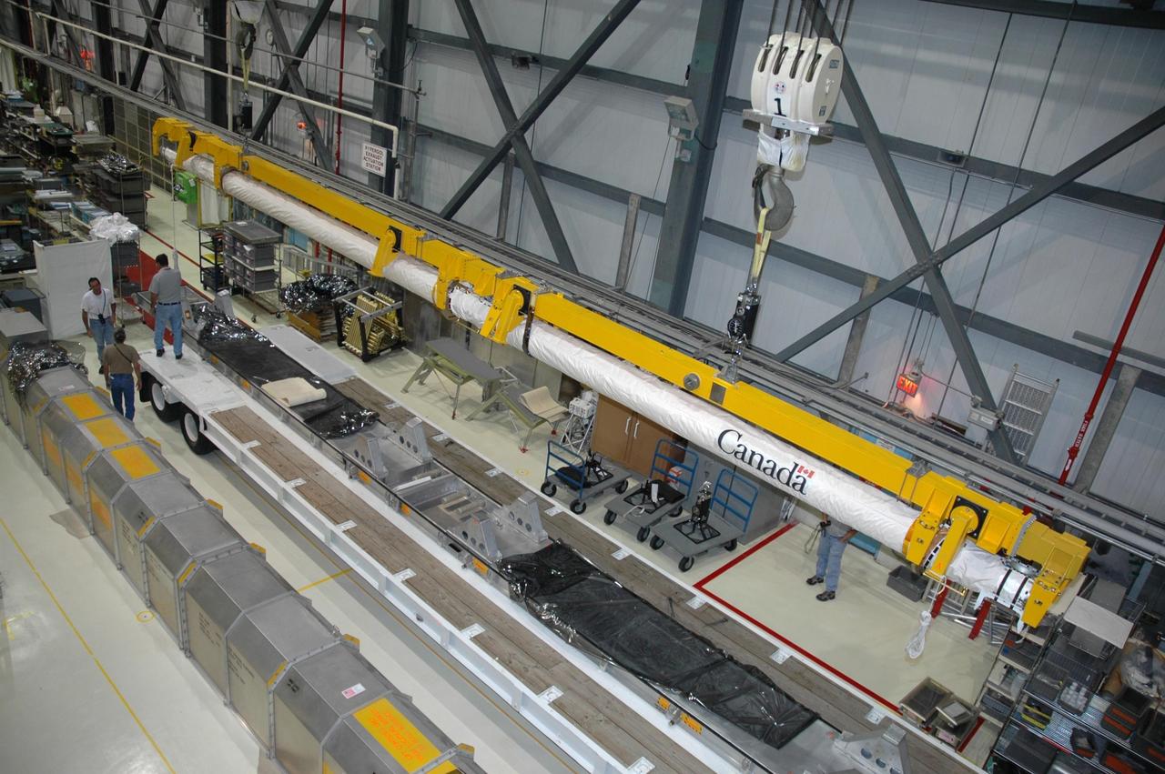 KENNEDY SPACE CENTER, FLA. -    In the Orbiter Processing Facility’s bay 1, the orbiter boom sensor system is lifted by a crane for installation on the starboard side of Atlantis’s payload bay for mission STS-117.  The 50-foot-long boom attaches to the shuttle arm and provides equipment to inspect the shuttle's heat shield while in space.  It contains an intensified television camera (ITVC) and a laser dynamic range imager, which are mounted on a pan and tilt unit, and a laser camera system (LCS) mounted on a stationary bracket. Mission STS-117 will carry the S3/S4 arrays for installation on the International Space Station.  Launch of Space Shuttle Atlantis is scheduled for March.  Photo credit: NASA/Jack Pfaller