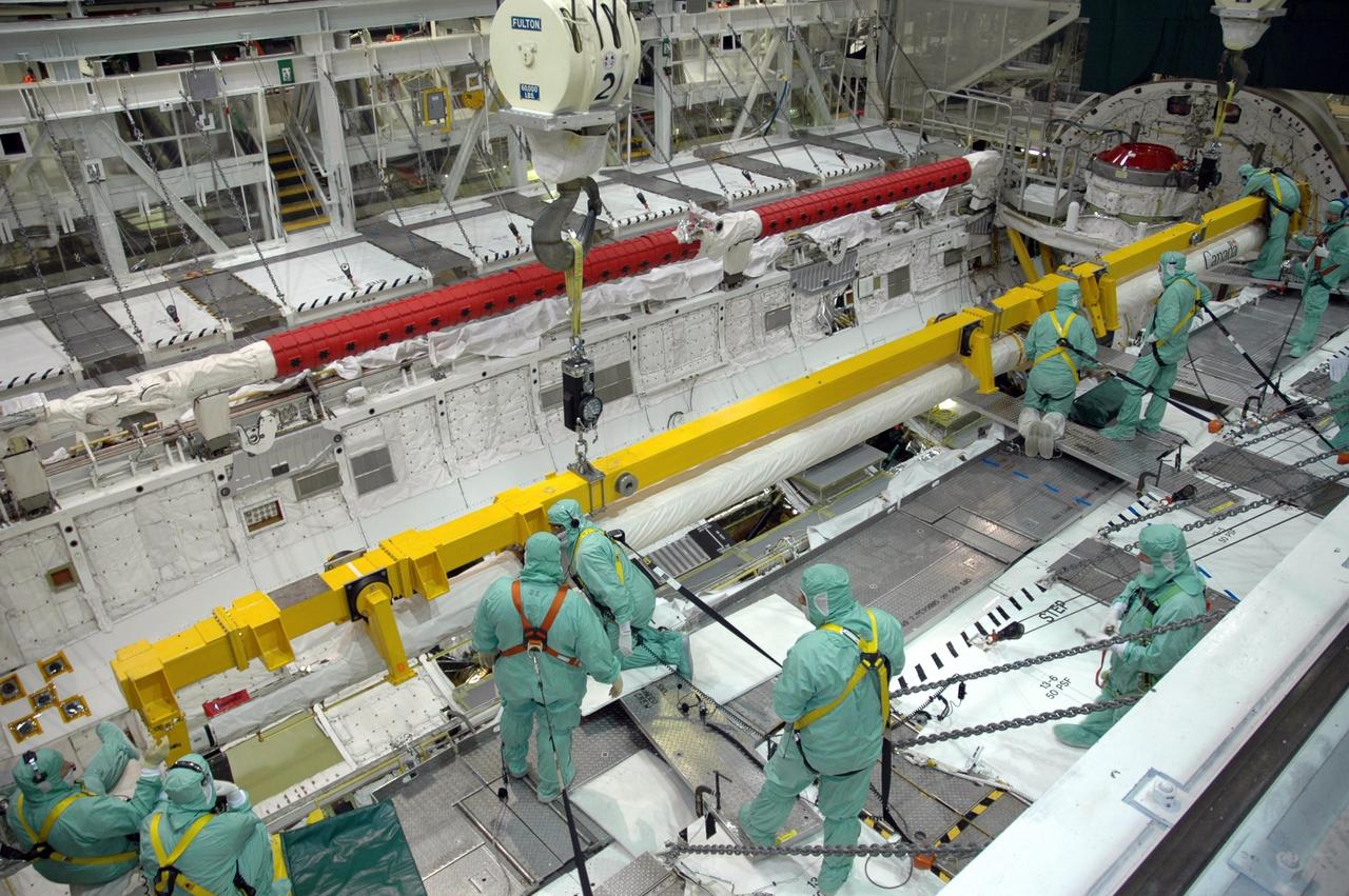 KENNEDY SPACE CENTER, FLA. -  In the Orbiter Processing Facility’s bay 1, workers are ready to secure the orbiter boom sensor system on the starboard side of Atlantis’s payload bay for mission STS-117. The 50-foot-long boom attaches to the shuttle arm and provides equipment to inspect the shuttle's heat shield while in space.  It contains an intensified television camera (ITVC) and a laser dynamic range imager, which are mounted on a pan and tilt unit, and a laser camera system (LCS) mounted on a stationary bracket. Mission STS-117 will carry the S3/S4 arrays for installation on the International Space Station.  Launch of Space Shuttle Atlantis is scheduled for March.  Photo credit: NASA/Jack Pfaller