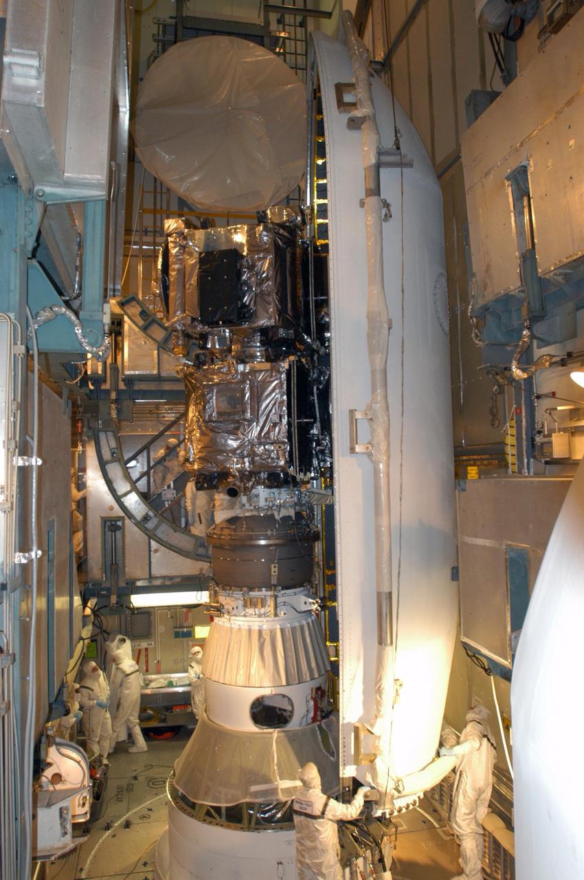 KENNEDY SPACE CENTER, FLA. -  Inside the mobile service tower on Launch Pad 17-B at Cape Canaveral Air Force Station, workers help maneuver one segment of the fairing around the STEREO spacecraft.  The fairing is a molded structure that fits flush with the outside surface of the Delta II upper stage booster and forms an aerodynamically smooth nose cone, protecting the spacecraft during launch and ascent. The STEREO (Solar Terrestrial Relations Observatory) mission is the first to take measurements of the sun and solar wind in 3-dimension. This new view will improve our understanding of space weather and its impact on the Earth.  Designed and built by the Applied Physics Laboratory (APL) , the STEREO mission is being managed by NASA Goddard Space Flight Center. APL will maintain command and control of the observatories throughout the mission, while NASA tracks and receives the data, determines the orbit of the satellites, and coordinates the science results. STEREO is expected to lift off Oct. 25. Photo credit: NASA/George Shelton