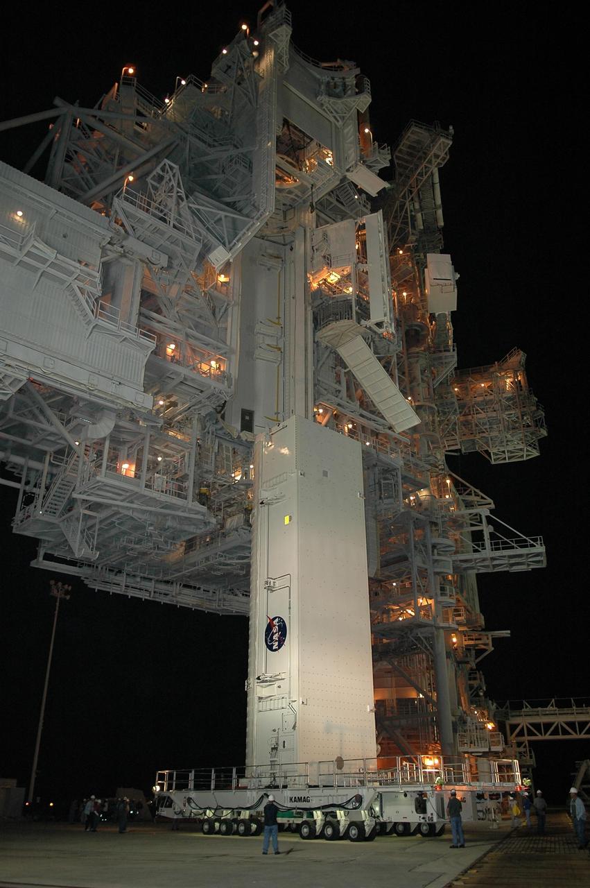 KENNEDY SPACE CENTER, FLA. --  The payload canister transporter and canister move into place under the payload changeout room (PCR) on the rotating service structure (RSS) on Launch Pad 39B.  Inside the canister are the SPACEHAB module and the port 5 truss segment for mission STS-116.  Once inside the PCR, they will be transferred into Space Shuttle Discovery's payload bay once the vehicle has rolled out to the pad. The PCR is the enclosed, environmentally controlled portion of the RSS that supports cargo delivery to the pad and subsequent vertical installation into the orbiter payload bay. Seals around the mating surface of the PCR fit against the orbiter and allow the opening of the payload bay or canister doors and removal of the cargo without exposure to outside air and contaminants. A clean-air purge in the PCR maintains environmental control during PCR cargo operations. Cargo is removed from the payload canister and installed vertically in the orbiter by the payload ground handling mechanism (PGHM). Photo credit: NASA/Kim Shiflett