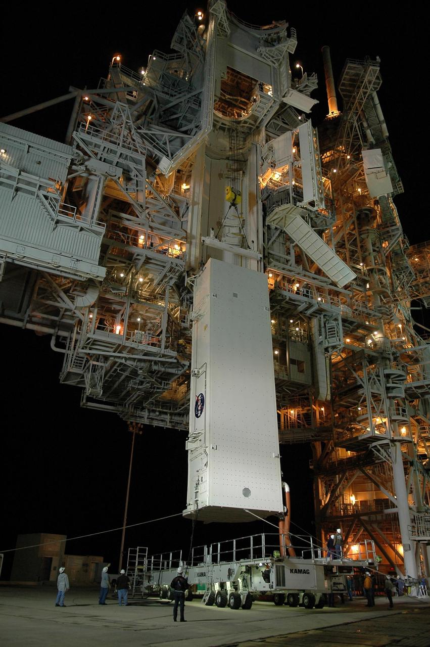KENNEDY SPACE CENTER, FLA. --   With umbilical lines still attached, the payload canister is lifted up to the payload changeout room (PCR) on the rotating service structure (RSS) on Launch Pad 39B.  Inside the canister are the SPACEHAB module and the port 5 truss segment for mission STS-116.  Once inside the PCR, they will be transferred into Space Shuttle Discovery's payload bay once the vehicle has rolled out to the pad.  On the right is the fixed service structure.  The PCR is the enclosed, environmentally controlled portion of the RSS that supports cargo delivery to the pad and subsequent vertical installation into the orbiter payload bay. Seals around the mating surface of the PCR fit against the orbiter and allow the opening of the payload bay or canister doors and removal of the cargo without exposure to outside air and contaminants. A clean-air purge in the PCR maintains environmental control during PCR cargo operations. Cargo is removed from the payload canister and installed vertically in the orbiter by the payload ground handling mechanism (PGHM). Photo credit: NASA/Kim Shiflett