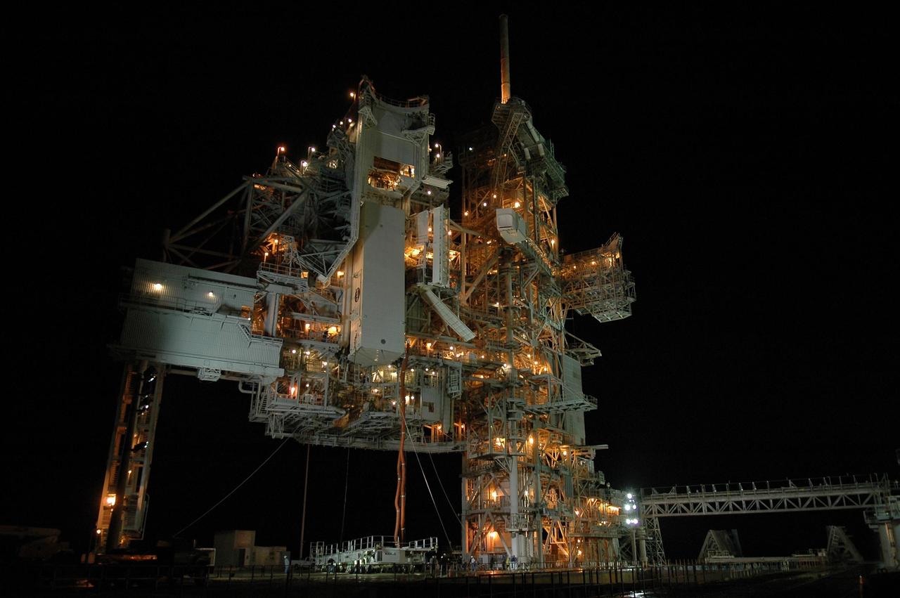 KENNEDY SPACE CENTER, FLA. --  With umbilical lines still attached, the payload canister is lifted up to the payload changeout room (PCR) on the rotating service structure (RSS) on Launch Pad 39B.  Inside the canister are the SPACEHAB module and the port 5 truss segment for mission STS-116.  Once inside the PCR, they will be transferred into Space Shuttle Discovery's payload bay once the vehicle has rolled out to the pad. On the right is the fixed service structure.  The PCR is the enclosed, environmentally controlled portion of the RSS that supports cargo delivery to the pad and subsequent vertical installation into the orbiter payload bay. Seals around the mating surface of the PCR fit against the orbiter and allow the opening of the payload bay or canister doors and removal of the cargo without exposure to outside air and contaminants. A clean-air purge in the PCR maintains environmental control during PCR cargo operations. Cargo is removed from the payload canister and installed vertically in the orbiter by the payload ground handling mechanism (PGHM). Photo credit: NASA/Kim Shiflett