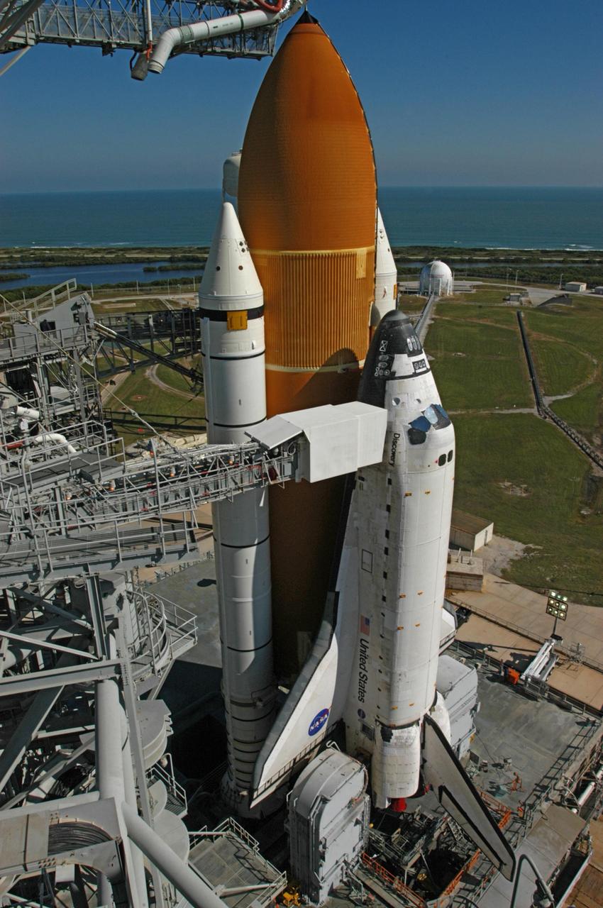 KENNEDY SPACE CENTER, FLA. --   Space Shuttle Discovery and the mobile launcher platform sit on Launch Pad 39B for mission STS-116. Beyond the pad is the Atlantic Ocean. The shuttle's external tank is capped by the oxygen vent hood (at top). Below it is the orbiter access arm which swings out from the fixed service structure to the orbiter crew compartment hatch to allow personnel to enter the crew compartment. The outer end of the access arm ends in an environmental chamber (white room) that mates with the orbiter and holds six persons. The arm remains in the extended position until seven minutes 24 seconds before launch to provide emergency egress for the flight crew. The rollout of Discovery from the Vehicle Assembly Building began at 12:29 a.m. The shuttle was harddown on the pad at 9:03 a.m. The mission is No. 20 to the International Space Station and construction flight 12A.1. The mission payload is the SPACEHAB module, the P5 integrated truss structure and other key components. The launch window for mission STS-116 opens Dec. 7.  Photo credit: NASA/George Shelton