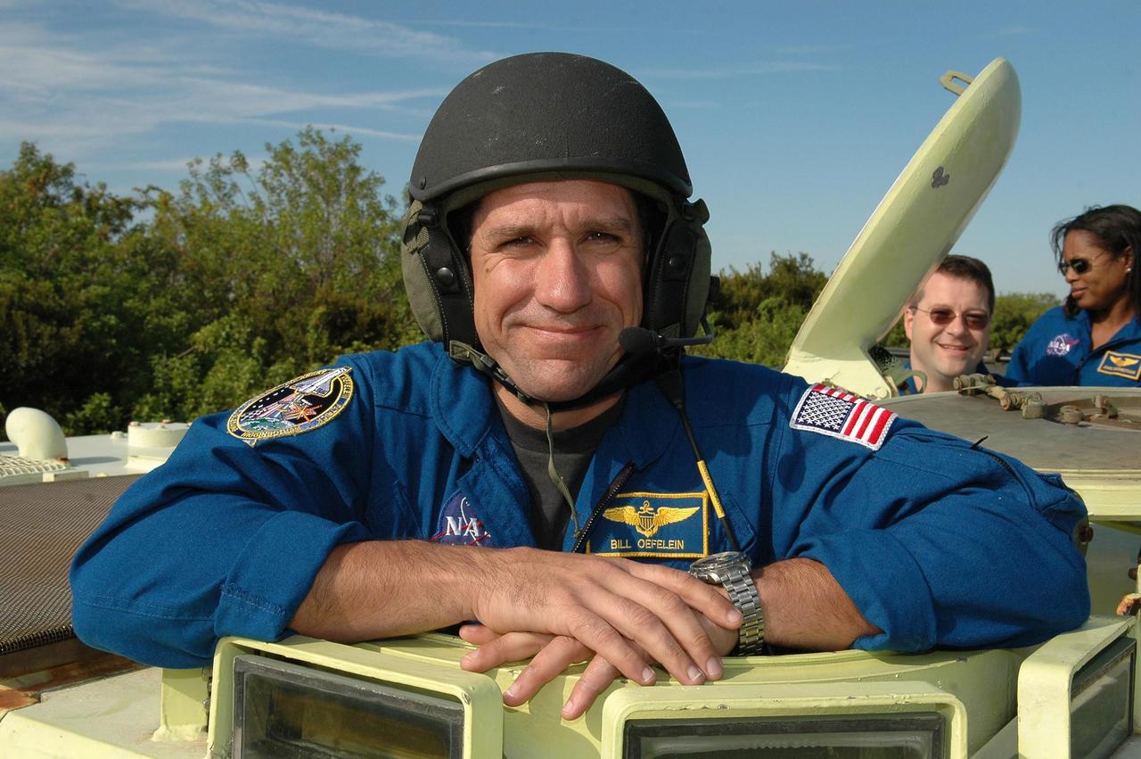 KENNEDY SPACE CENTER, FLA. -- STS-116 Pilot William Oefelein wears his helmet in preparation for driving the M-113 armored personnel carrier. The mission crew is at KSC for terminal countdown demonstration test (TCDT) activities that are preparation for launch. The M-113 could be used to move the crew quickly away from the launch pad in the event of an emergency. Behind Oefelein, at right, are Mission Specialists Nicholas Patrick and Joan Higginbotham. The STS-116 mission is No. 20 to the International Space Station and construction flight 12A.1. The mission payload is the SPACEHAB module, the P5 integrated truss structure and other key components. Launch is scheduled for no earlier than Dec. 7. Photo credit: NASA/Kim Shiflett