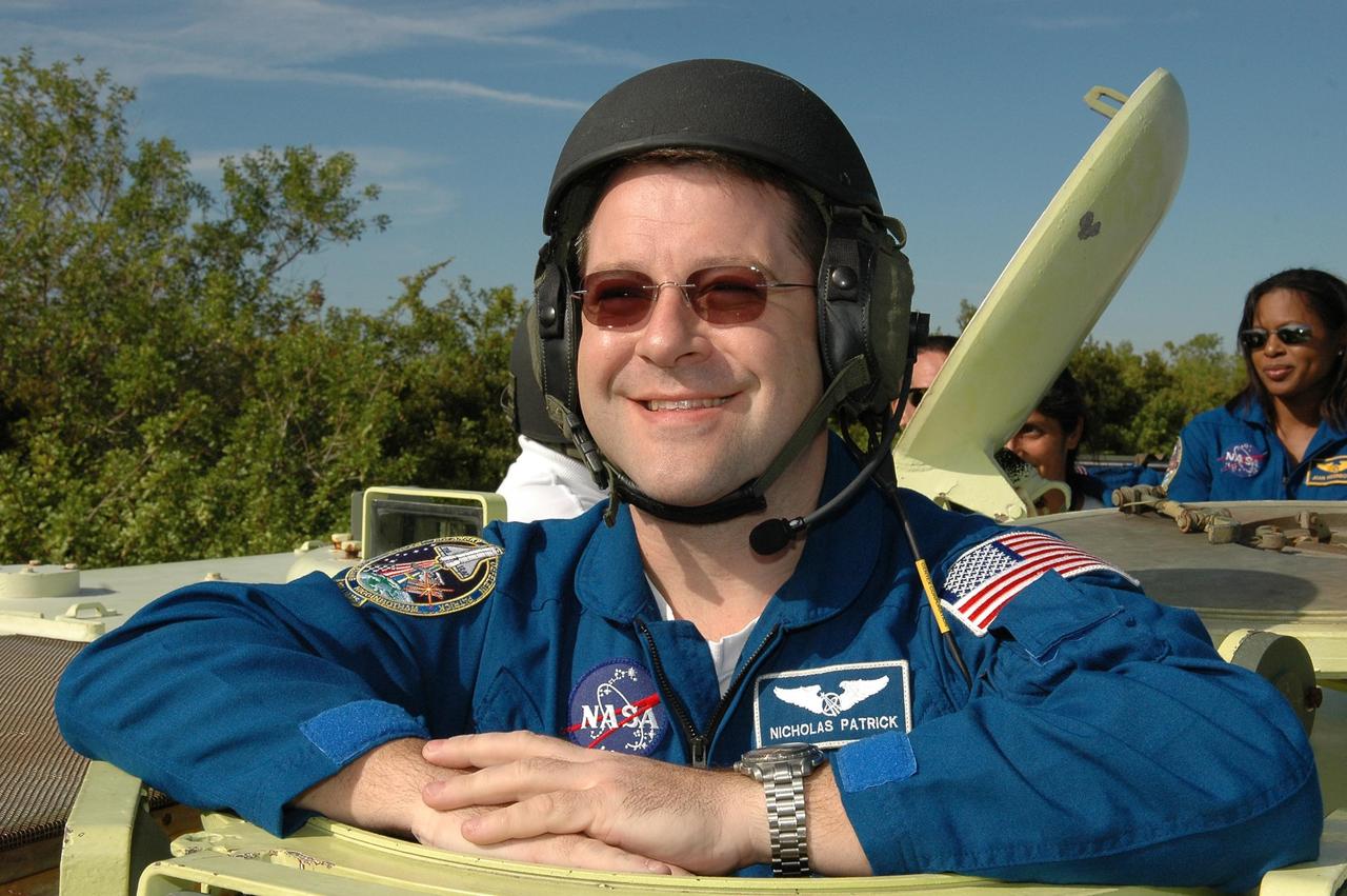 KENNEDY SPACE CENTER, FLA. -- STS-116 Mission Specialist Nicholas Patrick wears his helmet in preparation for driving the M-113 armored personnel carrier. The mission crew is at KSC for terminal countdown demonstration test (TCDT) activities that are preparation for launch. The M-113 could be used to move the crew quickly away from the launch pad in the event of an emergency. Behind Patrick, at right, are Pilot William Oefelein and Mission Specialists Sunita Williams and Joan Higginbotham. The STS-116 mission is No. 20 to the International Space Station and construction flight 12A.1. The mission payload is the SPACEHAB module, the P5 integrated truss structure and other key components. Launch is scheduled for no earlier than Dec. 7. Photo credit: NASA/Kim Shiflett