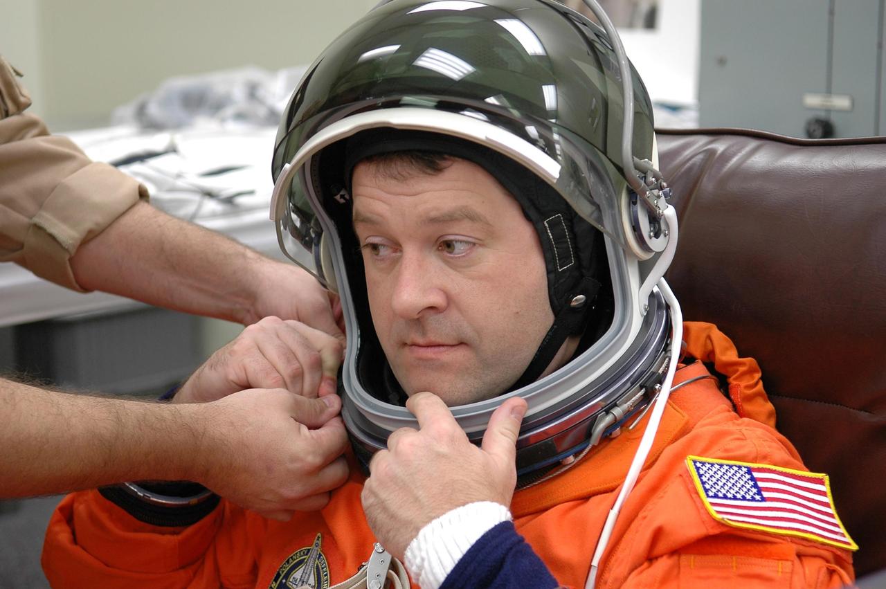KENNEDY SPACE CENTER, FLA. -- STS-116 Mission Specialist Nicholas Patrick is helped putting on his helmet during suit fit-check, part of the prelaunch preparations during terminal countdown demonstration test (TCDT) activities. The mission crew is at KSC for the TCDT, which includes a simulated launch countdown. The STS-116 mission is No. 20 to the International Space Station and construction flight 12A.1. The mission payload is the SPACEHAB module, the P5 integrated truss structure and other key components. Launch is scheduled for no earlier than Dec. 7. Photo credit: NASA/Kim Shiflett