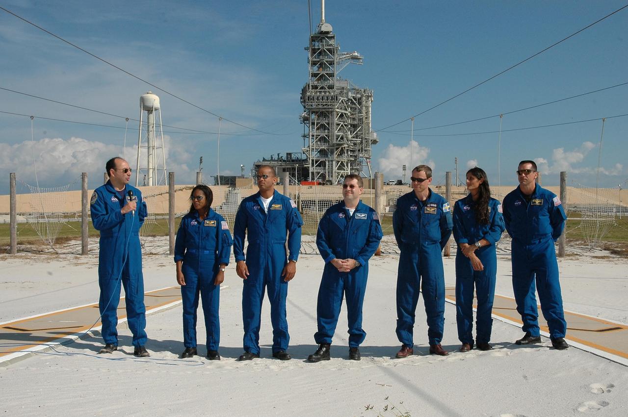KENNEDY SPACE CENTER, FLA. -- The STS-116 crew pause in their prelaunch activities to talk to the media at Launch Pad 39B. With the microphone, at left, is Commander Mark Polansky. The other crew members are, from left, Mission Specialists Joan Higginbotham, Robert Curbeam, Nicholas Patrick, Christer Fuglesang and Sunita Williams, and Pilot William Oefelein. Fuglesang represents the European Space Agency. The mission crew is at KSC for the TCDT, which includes a simulated launch countdown. The STS-116 mission is No. 20 to the International Space Station and construction flight 12A.1. The mission payload is the SPACEHAB module, the P5 integrated truss structure and other key components. Launch is scheduled for no earlier than Dec. 7. Photo credit: NASA/Kim Shiflett