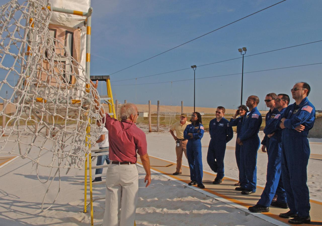 KENNEDY SPACE CENTER, FLA. --   At the slidewire basket landing area at Launch Pad 39B, STS-116 crew members get instructions for exiting the baskets used for emergency egress from the orbiter.  Standing at right are (from left) Mission Specialists Joan Higginbotham, Nicholas Patrick, Sunita Williams, Robert Curbeam and Christer Fuglesang; Pilot William Oefelein; and Commander Mark Polansky.  The STS-116 mission is No. 20 to the International Space Station and construction flight 12A.1.  The mission payload is the SPACEHAB module, the P5 integrated truss structure and other key components. Launch is scheduled for no earlier than Dec. 7.  Photo credit: NASA/Kim Shiflett