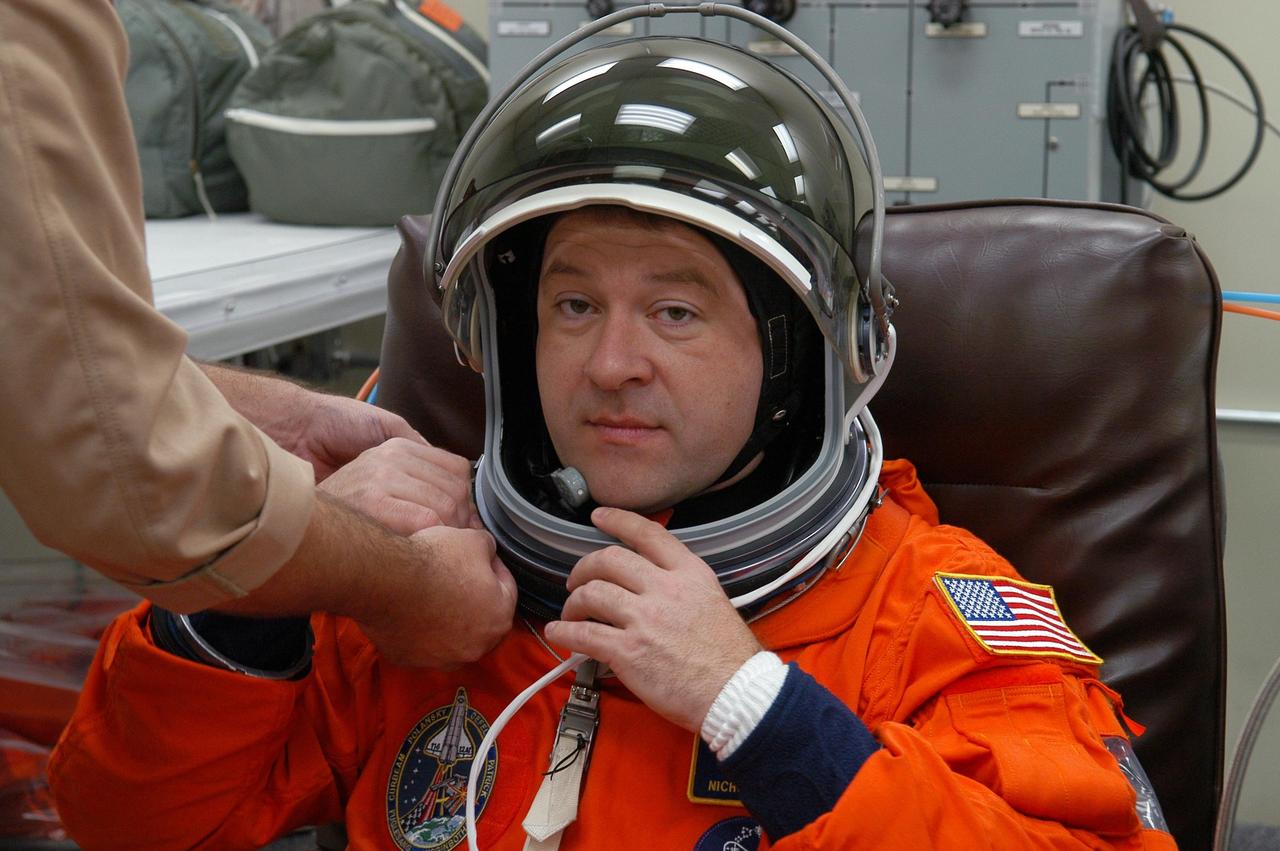 KENNEDY SPACE CENTER, FLA. -- The STS-116 mission crew practices for launch with a simulation of activities, from crew breakfast and suit-up to countdown in the orbiter. In this photo Mission Specialist Nicholas Patrick puts on his helmet before heading to Launch Pad 39B. The STS-116 mission is No. 20 to the International Space Station and construction flight 12A.1. The mission payload is the SPACEHAB module, the P5 integrated truss structure and other key components. Launch is scheduled for no earlier than Dec. 7. Photo credit: NASA/Kim Shiflett