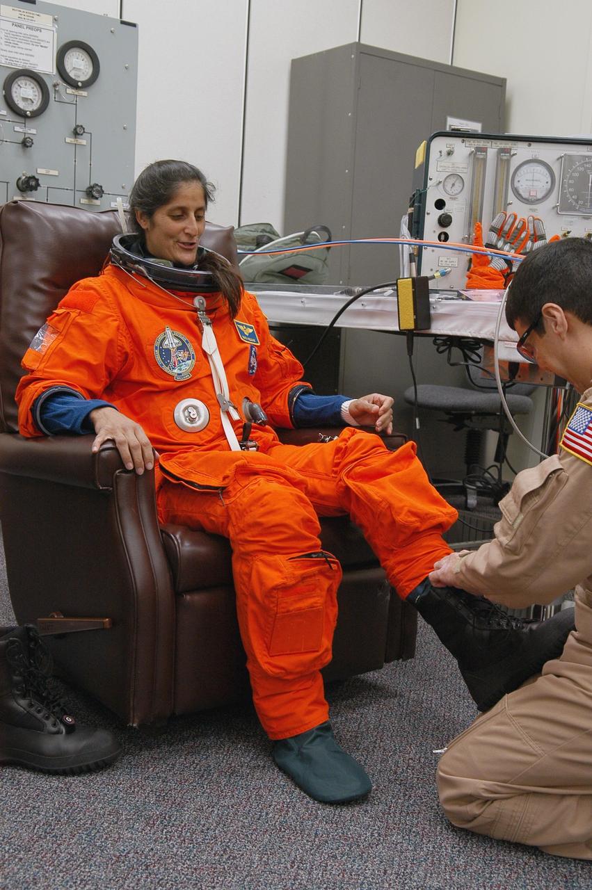 KENNEDY SPACE CENTER, FLA. -- The STS-116 mission crew practices for launch with a simulation of activities, from crew breakfast and suit-up to countdown in the orbiter. In this photo Mission Specialist Sunita Williams is helped with her boot before heading to Launch Pad 39B. The STS-116 mission is No. 20 to the International Space Station and construction flight 12A.1. The mission payload is the SPACEHAB module, the P5 integrated truss structure and other key components. Launch is scheduled for no earlier than Dec. 7. Photo credit: NASA/Kim Shiflett