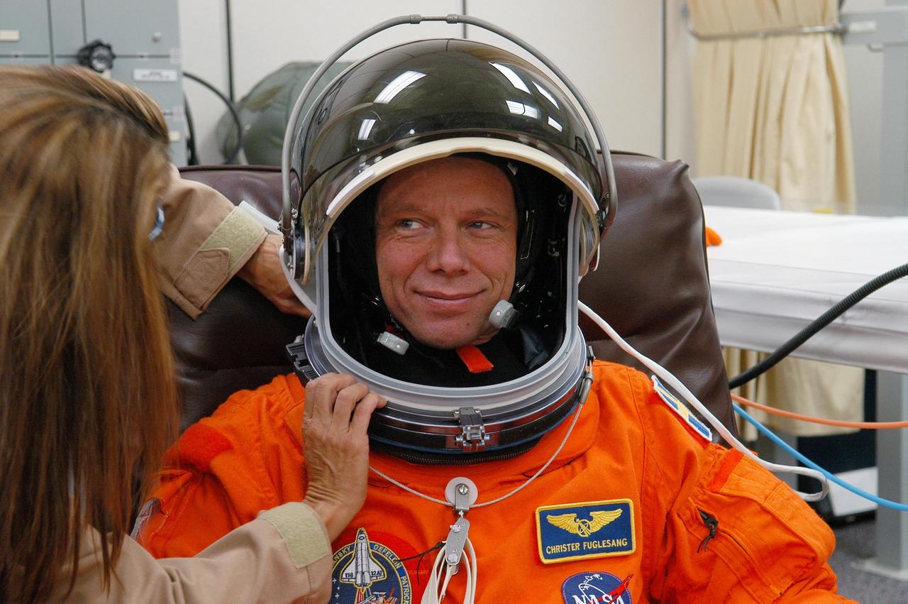 KENNEDY SPACE CENTER, FLA. -- The STS-116 mission crew practices for launch with a simulation of activities, from crew breakfast and suit-up to countdown in the orbiter. In this photo Mission Specialist Christer Fuglesang, who represents the European Space Agency, has help with his helmet before heading to Launch Pad 39B. The STS-116 mission is No. 20 to the International Space Station and construction flight 12A.1. The mission payload is the SPACEHAB module, the P5 integrated truss structure and other key components. Launch is scheduled for no earlier than Dec. 7. Photo credit: NASA/Kim Shiflett