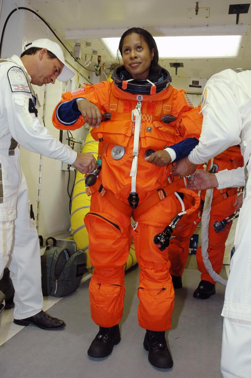 KENNEDY SPACE CENTER, FLA. --  In the white room on Launch Pad 39B, STS-116 Mission Specialist Joan Higginbotham is helped with her gear before entering Space Shuttle Discovery. The mission crew is taking part in a simulated launch countdown, part of the terminal countdown demonstration test that includes prelaunch preparations. The STS-116 mission is No. 20 to the International Space Station and construction flight 12A.1. The mission payload is the SPACEHAB module, the P5 integrated truss structure and other key components. Launch is scheduled for no earlier than Dec. 7. Photo credit: NASA/Amanda Diller