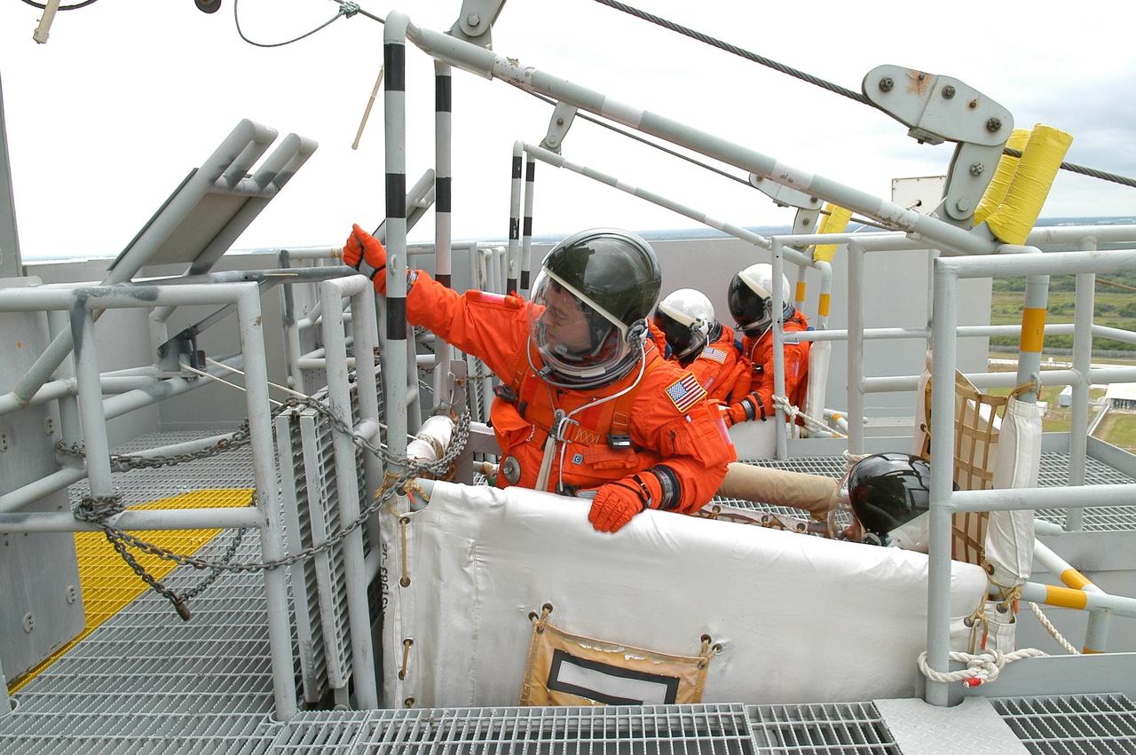 KENNEDY SPACE CENTER, FLA. -- From the 195-foot level of the fixed service structure on Launch Pad 39B, STS-116 Mission Specialist Nicholas Patrick sit in a slidewire basket, part of the emergency egress system. Behind him in the basket is Mission Specialist Robert Curbeam. He and other crew members are practicing the procedure to get off the pad that are part of the prelaunch preparations known as terminal countdown demonstration test. The TCDT includes a simulated launch countdown and payload familiarization. The STS-116 mission is No. 20 to the International Space Station and construction flight 12A.1. The mission payload is the SPACEHAB module, the P5 integrated truss structure and other key components. Launch is scheduled for no earlier than Dec. 7. Photo credit: NASA/Kim Shiflett