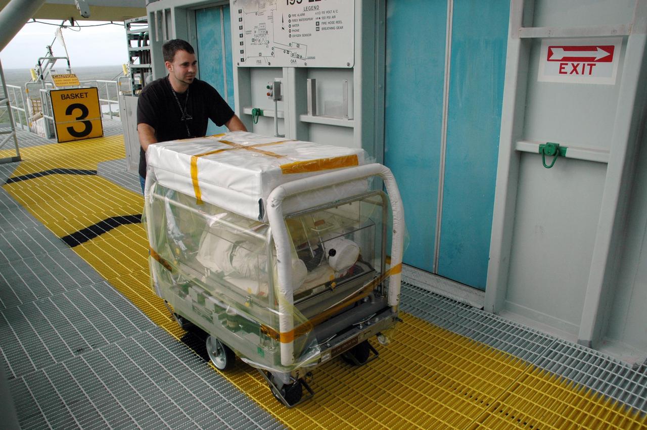 KENNEDY SPACE CENTER, FLA. --  A worker on Launch Pad 39B arrives on the 195-foot level of the fixed service structure with a cart containing the extravehicular mobility units (or spacewalk suits) to be used on mission STS-116.  The suits will be stored inside Space Shuttle Discovery. Launch of Discovery is scheduled for 9:35 p.m. Dec. 7. The crew will deliver the P5 integrated truss to the International Space Station and install it during one or more extravehicular activities. Photo credit: NASA/Jack Pfaller