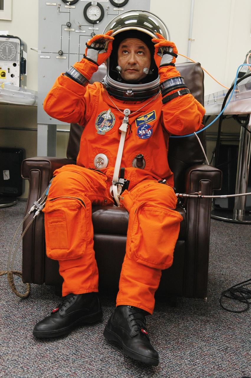 KENNEDY SPACE CENTER, FLA. --  STS-116 Commander Mark Polansky adjusts his helmet during a suit fit-check.  Polansky has returned from practicing landing the orbiter at the controls of the shuttle training aircraft.  The STA is a Grumman American Aviation-built Gulf Stream II jet that was modified to simulate an orbiter's cockpit, motion and visual cues, and handling qualities. In flight, the STA duplicates the orbiter's atmospheric descent trajectory from approximately 35,000 feet altitude to landing on a runway. Because the orbiter is unpowered during re-entry and landing, its high-speed glide must be perfectly executed the first time. Launch of Space Shuttle Discovery on mission STS-116 is scheduled for 9:35 p.m. Dec. 7. On the mission, the STS-116 crew will deliver truss segment, P5, to the International Space Station and begin the intricate process of reconfiguring and redistributing the power generated by two pairs of U.S. solar arrays. The P5 will be mated to the P4 truss that was delivered and attached during the STS-115 mission in September. Photo credit: NASA/Kim Shiflett