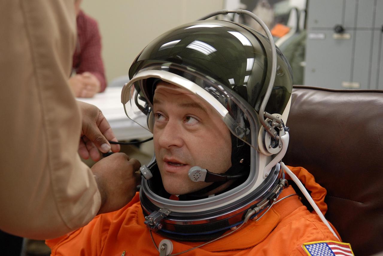 KENNEDY SPACE CENTER, FLA. --  The crew members of mission STS-116 are suiting up for launch at 9:35 p.m. EST from Launch Pad 39B aboard Space Shuttle Discovery.  Pictured here is Mission Specialist Nicholas Patrick, who will be making his first shuttle flight, being helped with his helmet. This is Discovery's 33rd mission and the first night launch since 2003.   The 20th shuttle mission to the International Space Station, STS-116 carries another truss segment, P5. It will serve as a spacer, mated to the P4 truss that was attached in September.  After installing the P5, the crew will reconfigure and redistribute the power generated by two pairs of U.S. solar arrays. Landing is expected Dec. 19 at KSC.   Photo credit: NASA/Kim Shiflett