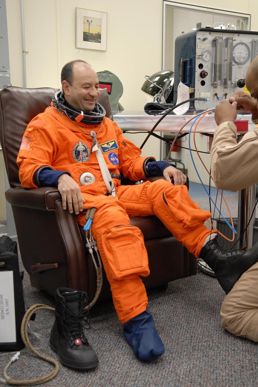 KENNEDY SPACE CENTER, FLA. --  The crew members of mission STS-116 are suiting up for launch at 9:35 p.m. EST from Launch Pad 39B aboard Space Shuttle Discovery.  Pictured here is Commander Mark Polansky, being helped with his boot.  Polansky will be making his second shuttle flight.  This is Discovery's 33rd mission and the first night launch since 2003.   The 20th shuttle mission to the International Space Station, STS-116 carries another truss segment, P5. It will serve as a spacer, mated to the P4 truss that was attached in September.  After installing the P5, the crew will reconfigure and redistribute the power generated by two pairs of U.S. solar arrays. Landing is expected Dec. 19 at KSC.   Photo credit: NASA/Kim Shiflett